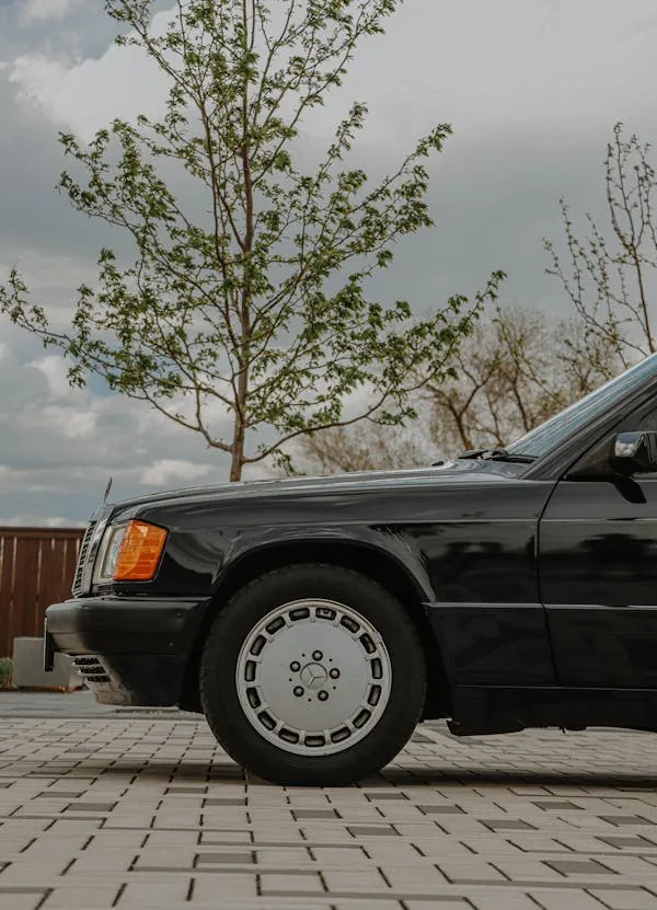 Old black Mercedes parked near paved modern lot image