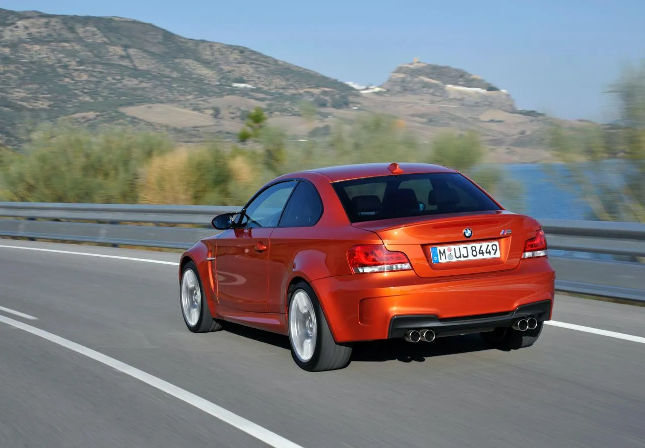 Orange Bmw Driving on Scenic Road with Hills Background