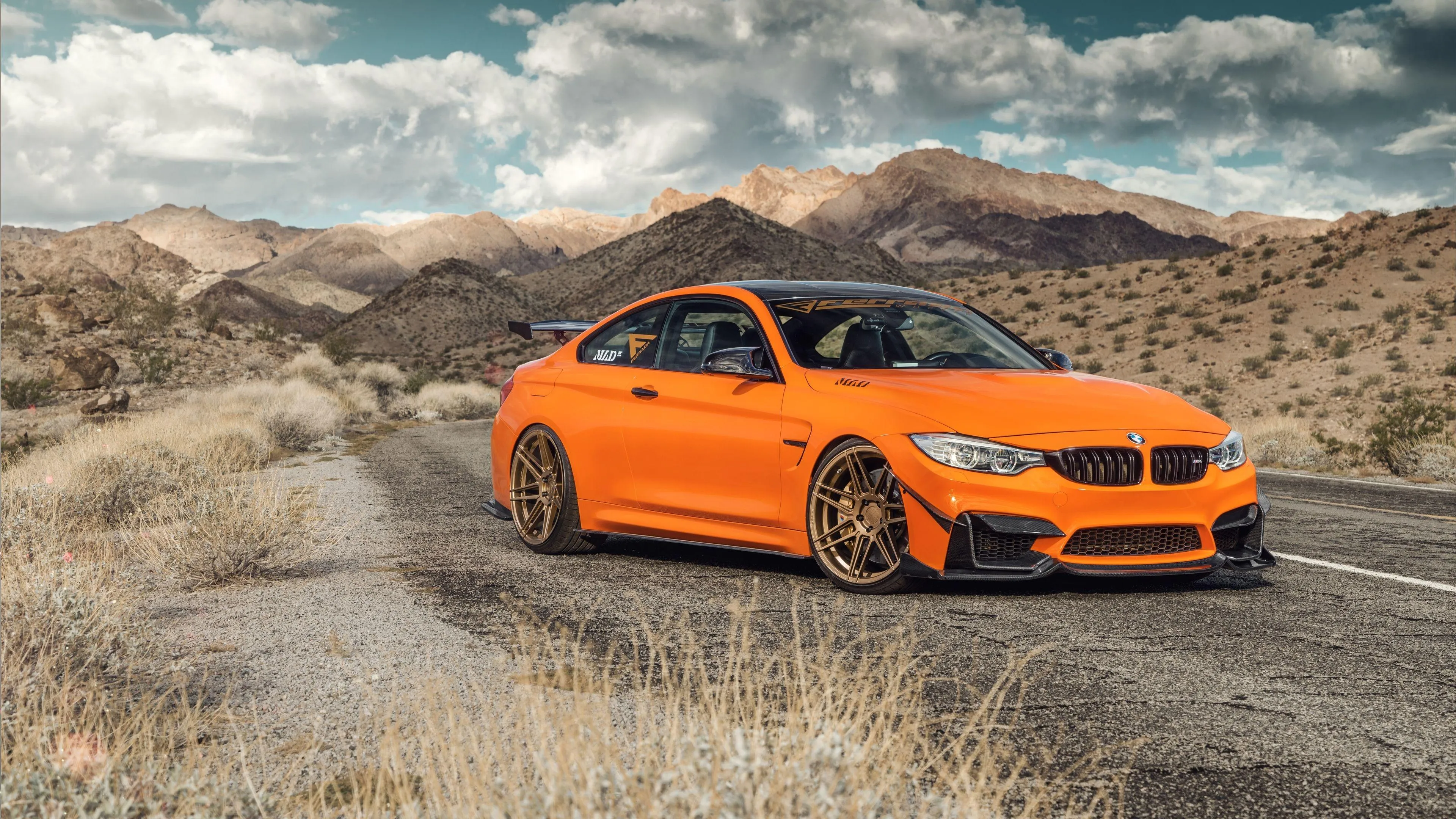 Orange Bmw Driving Through a Dusty Desert Road in Daylight