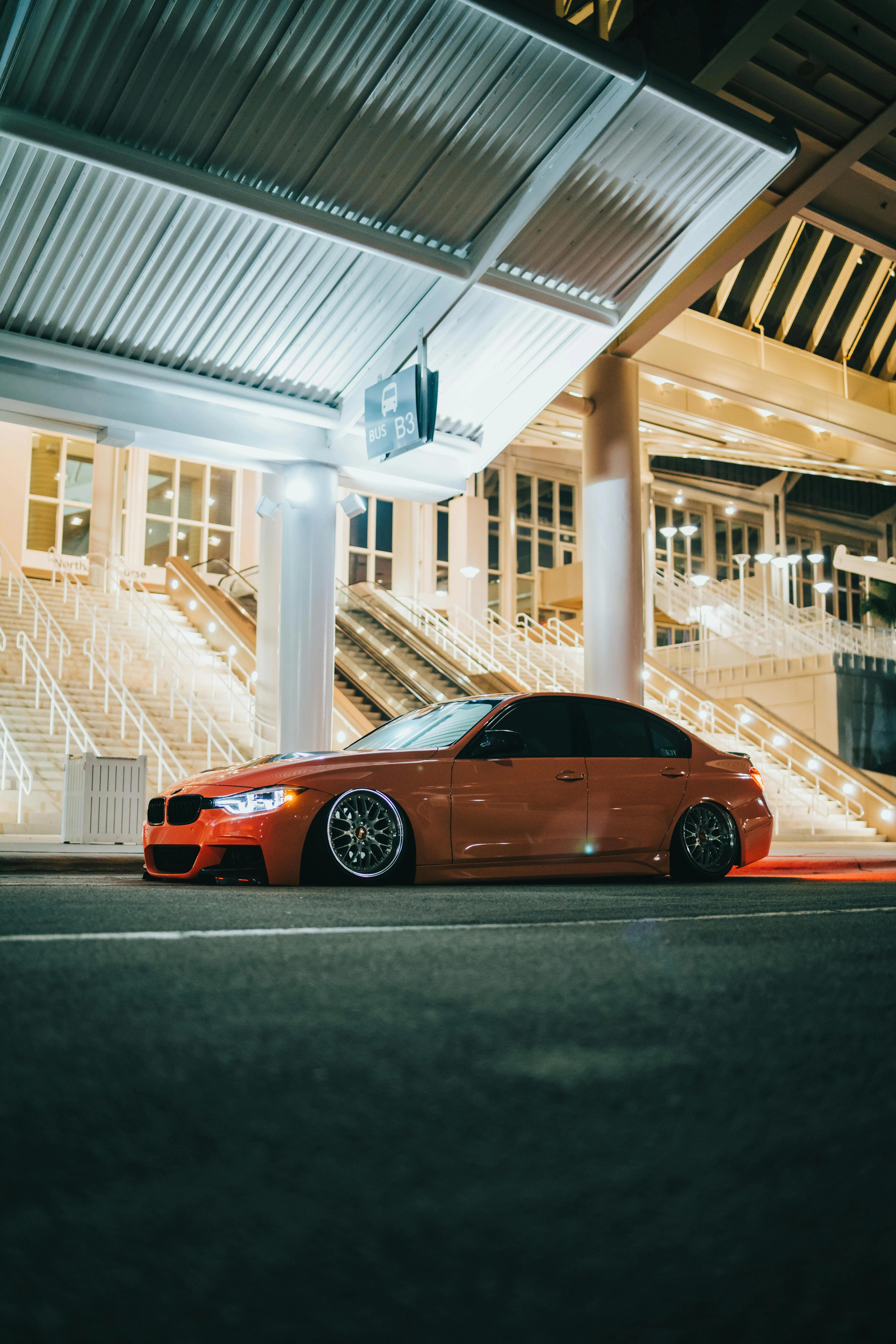 Orange Bmw Parked Under a Bright Modern Architecture