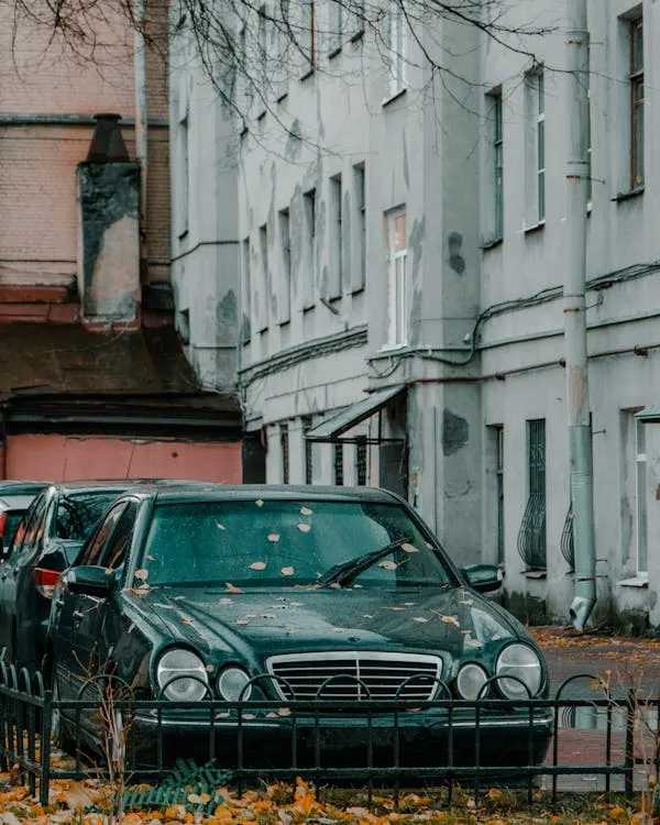 Parked Mercedes sedans outside worn residential building