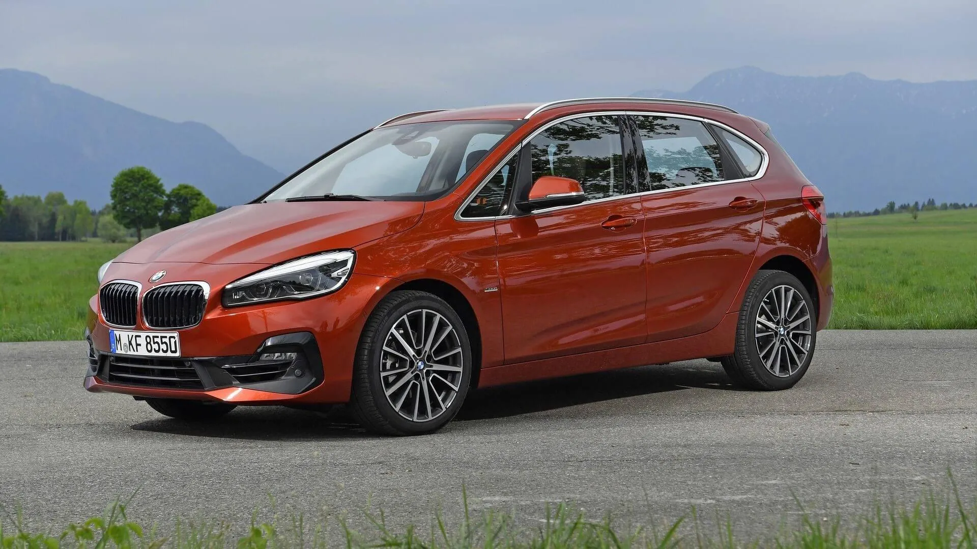 Red Bmw Compact Mpv Parked on a Grassy Field Roadside