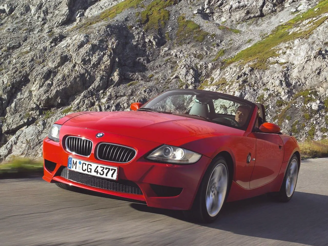 Red Bmw Convertible Driving Through Mountain Road Wallpaper