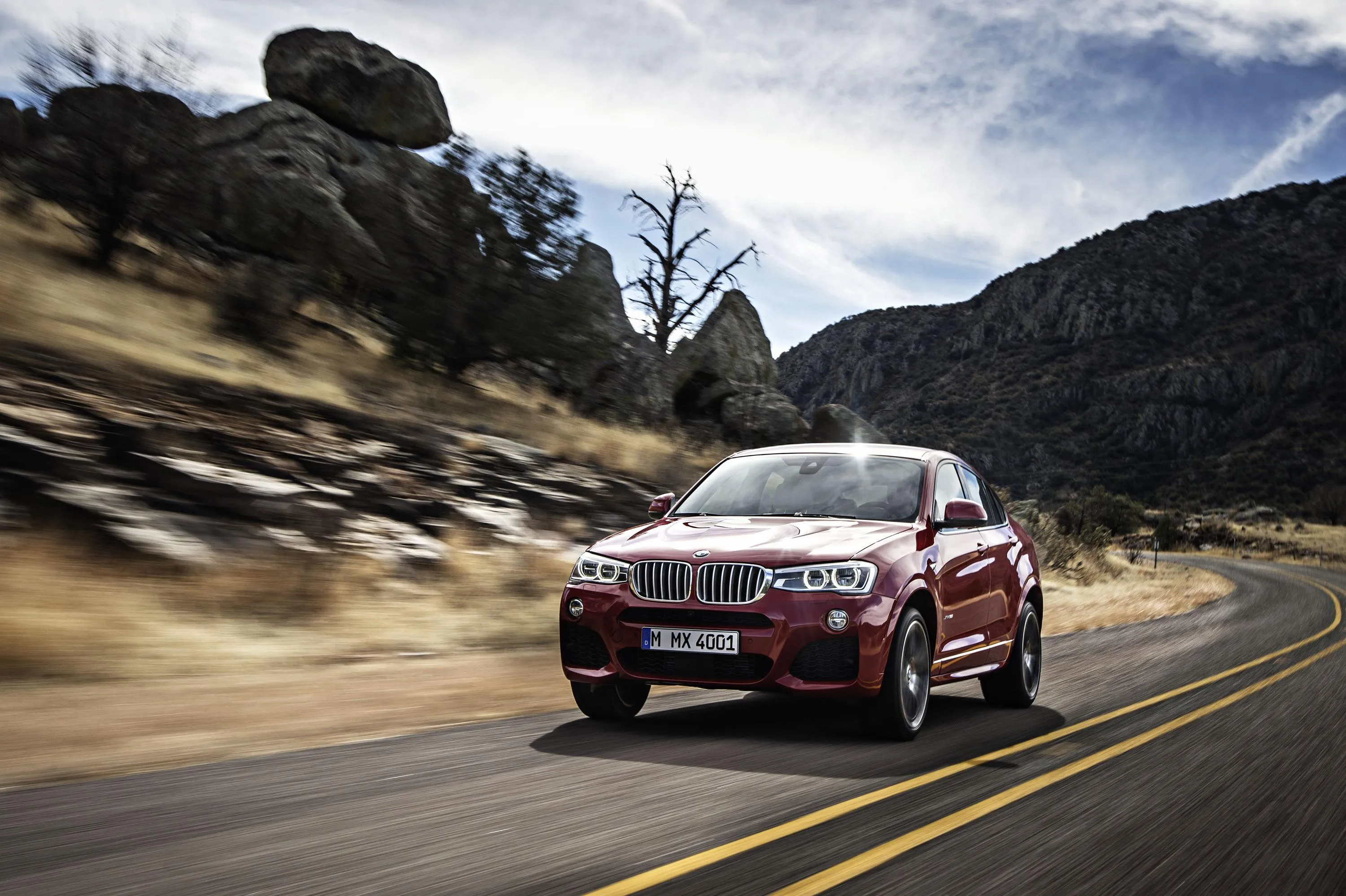 Red Bmw Driving on Mountain Road with Trees and Rocks