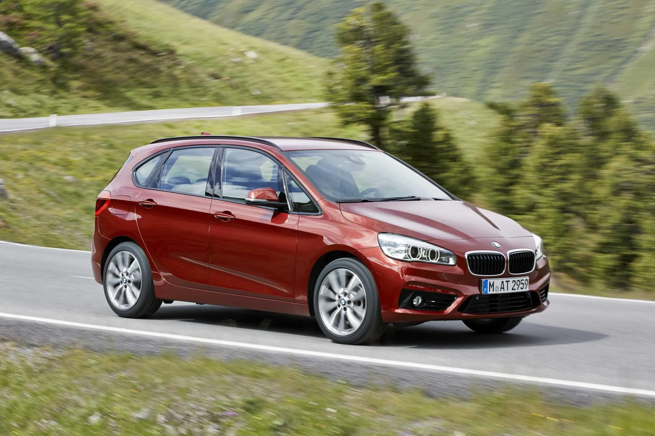 Red Bmw Hatchback Driving Through Scenic Hills Wallpaper
