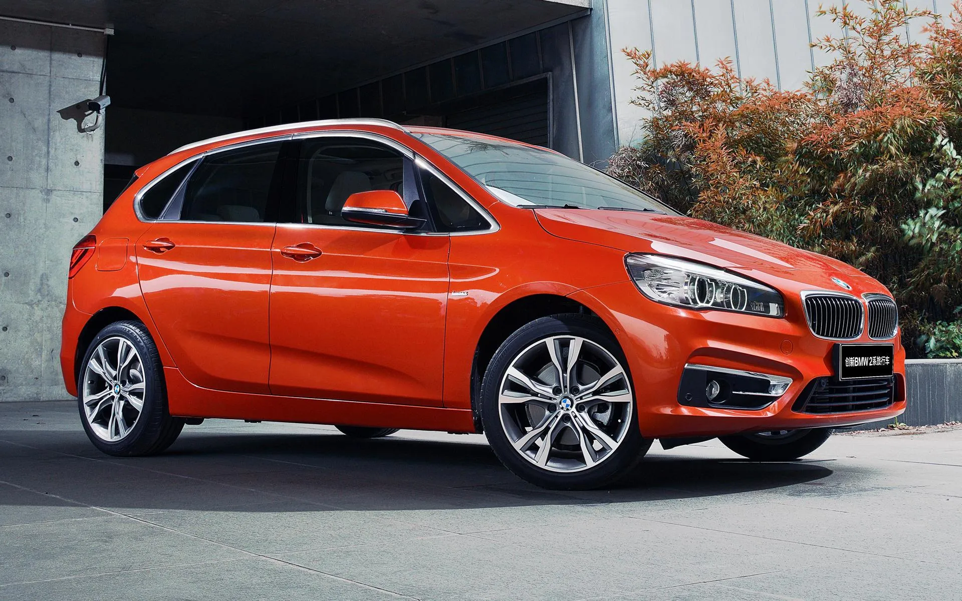 Red Bmw Hatchback Parked Near a Building with Autumn Trees