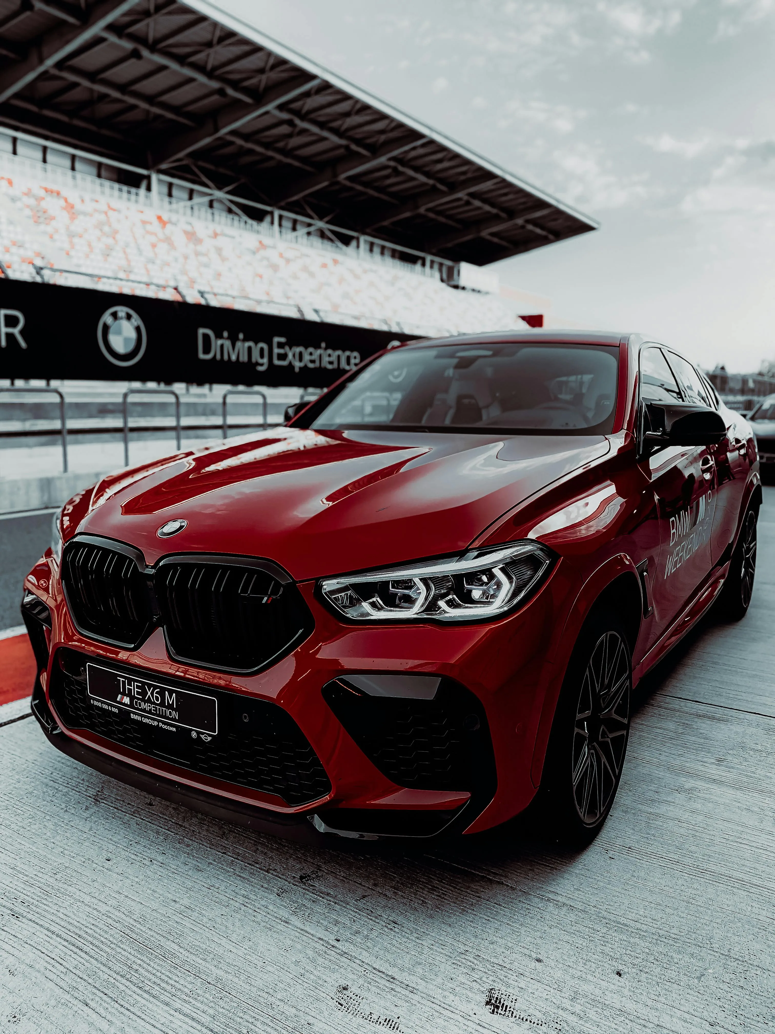Red Bmw Parked at Racetrack in Front of Grandstand