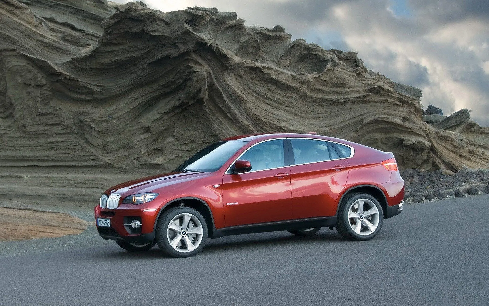 Red Bmw Parked Near Rocky Desert Terrain Hd Wallpaper