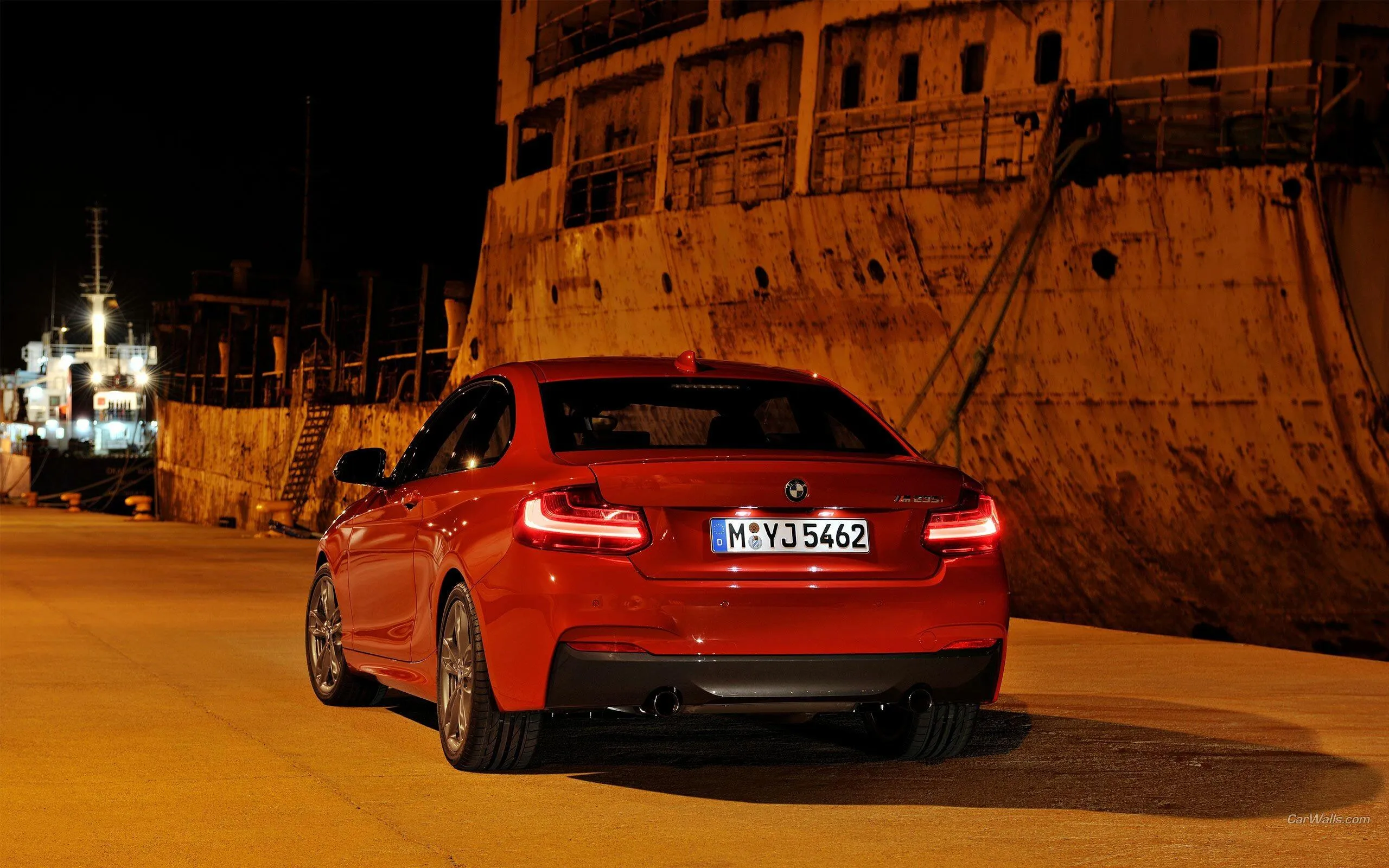 Red Bmw Parked Under Warm City Lights Near Buildings
