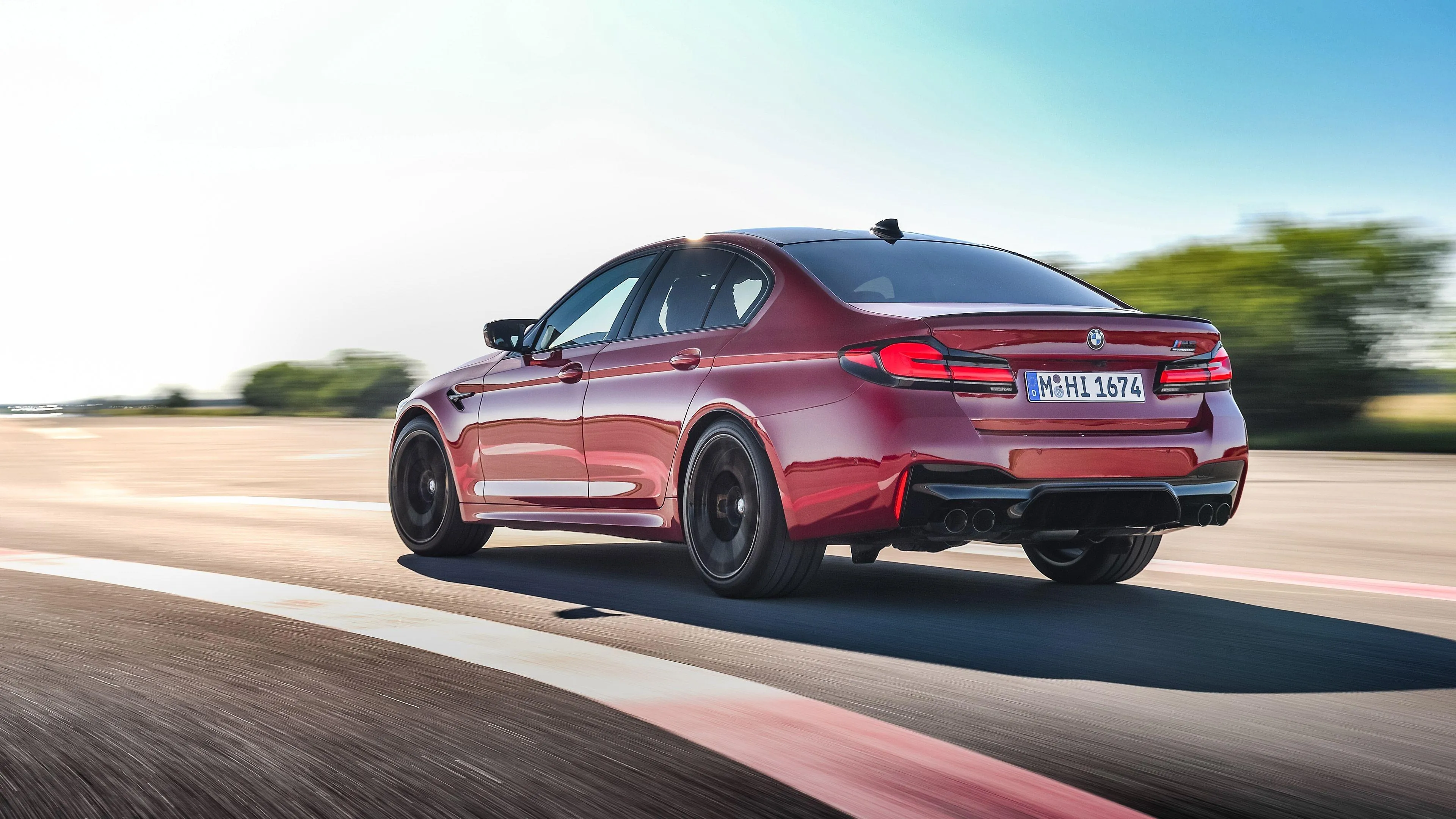 Red Bmw Sedan Racing on Track in Sunny Outdoor Setting
