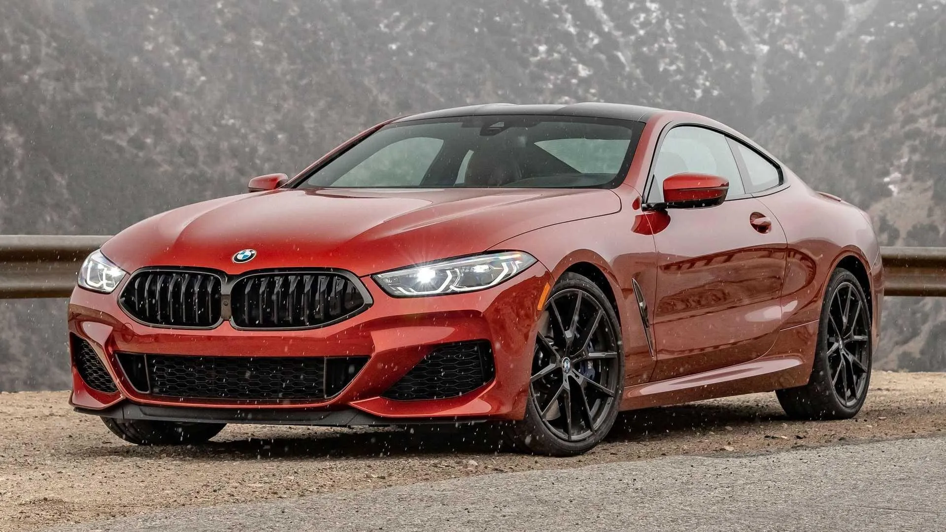 Red Bmw Sports Coupe on Sand Lot with Cloudy Sky Backdrop