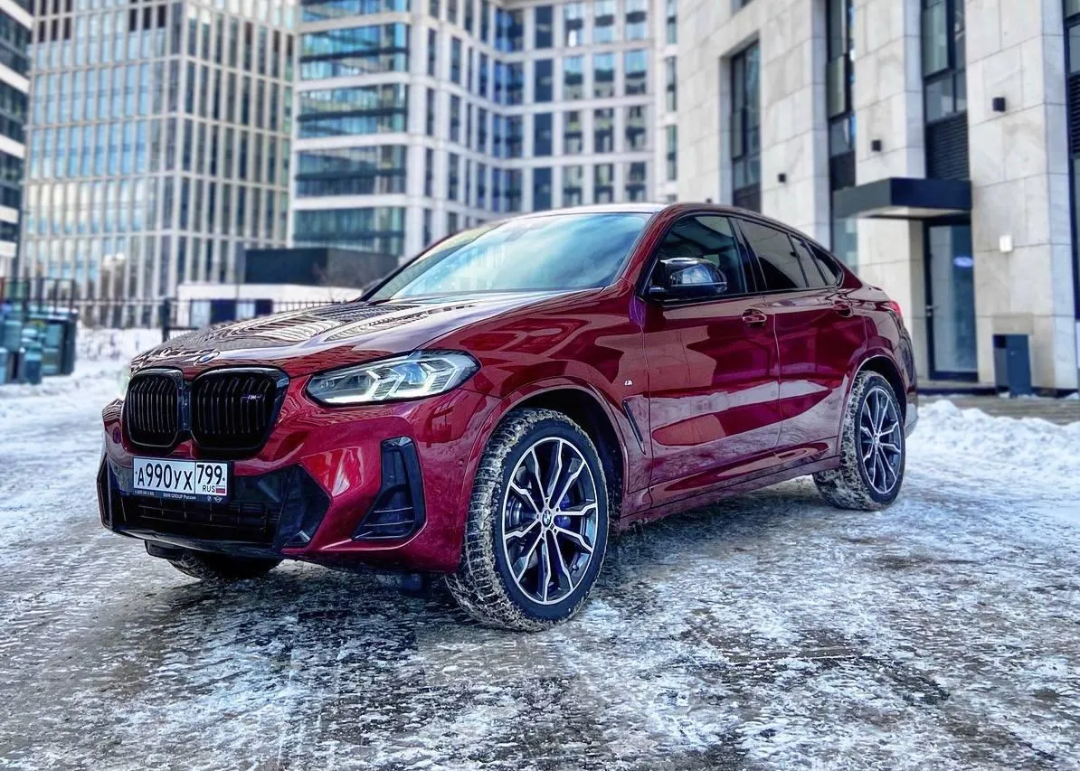 Red Bmw Suv Covered in Snow Parked Near Modern Buildings