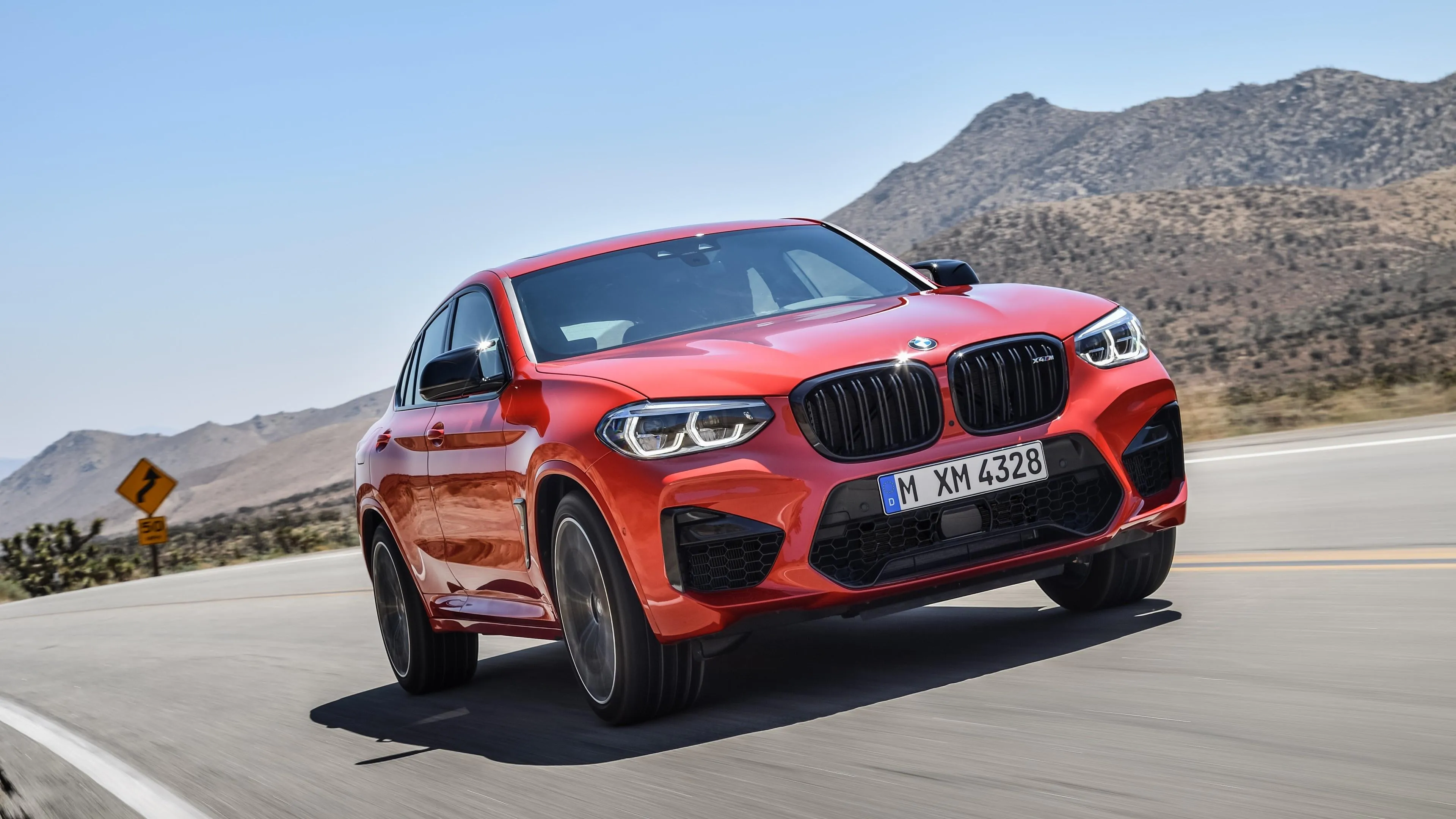 Red Bmw Suv Driving Fast Through Desert Highway Curve