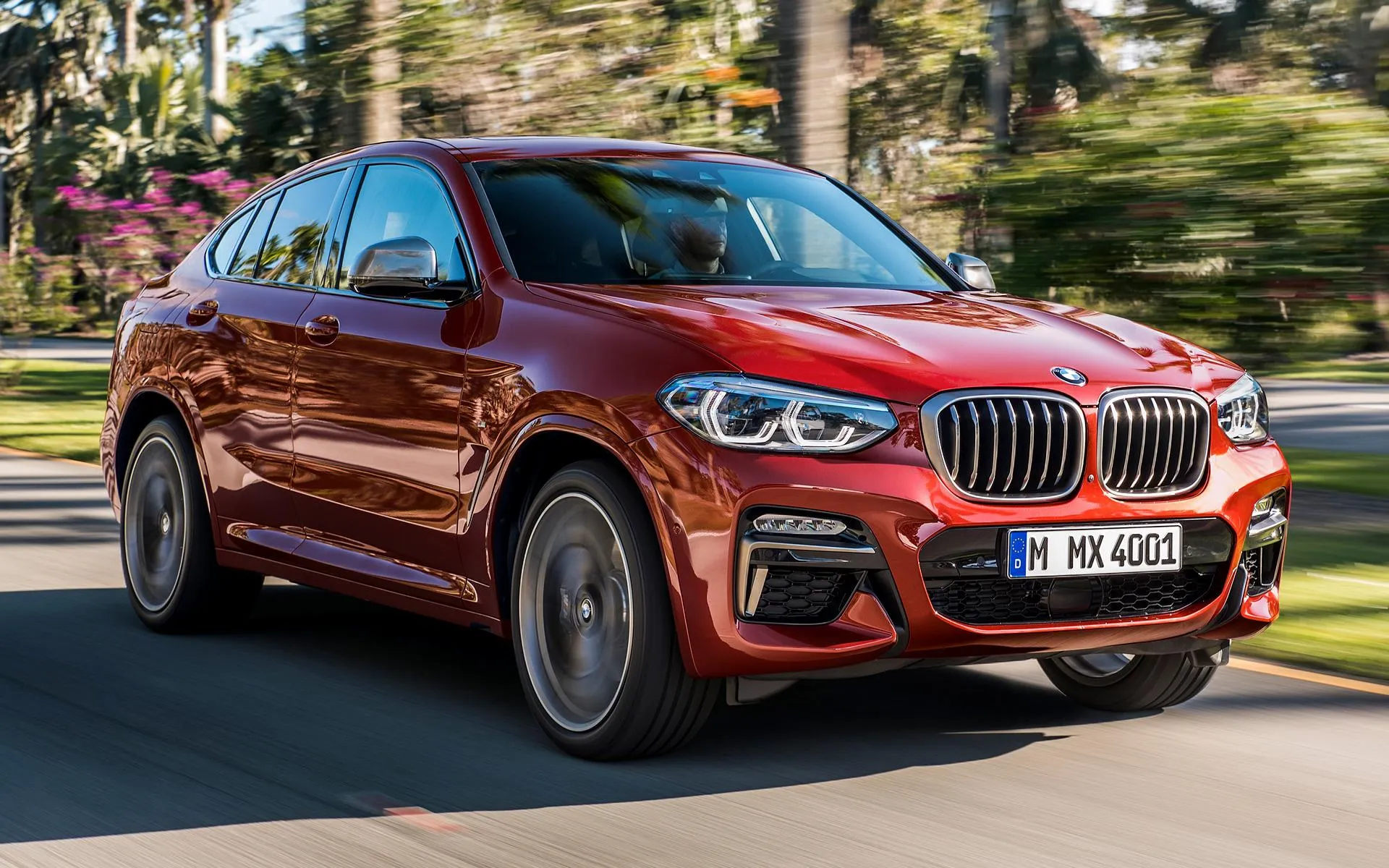 Red Bmw Suv Driving in a Lush Green Urban Park Wallpaper