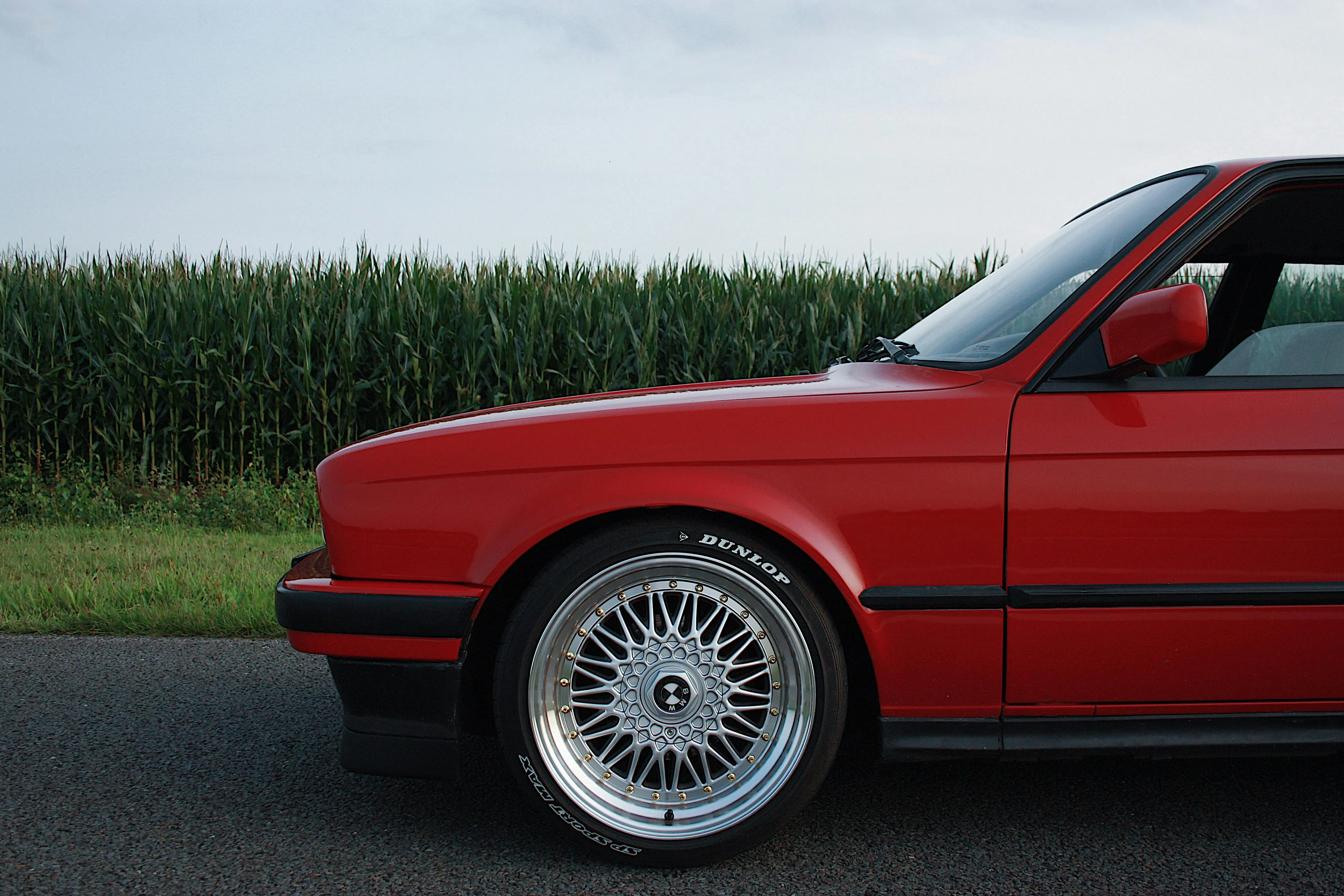 Red Classic Bmw Parked Near Field with Clear Sky Behind