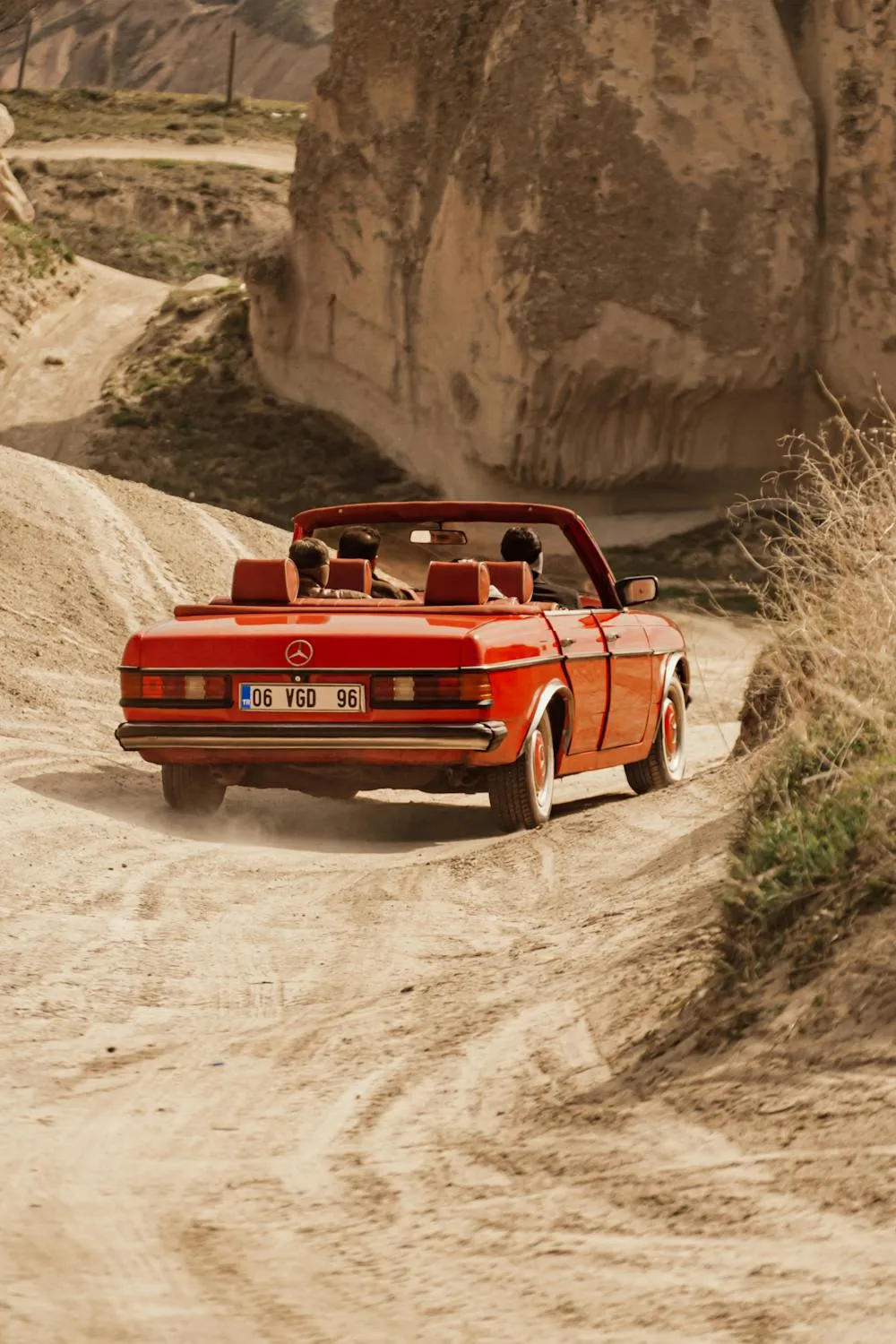 Red Classic Mercedes Driving Through Sandy Terrain