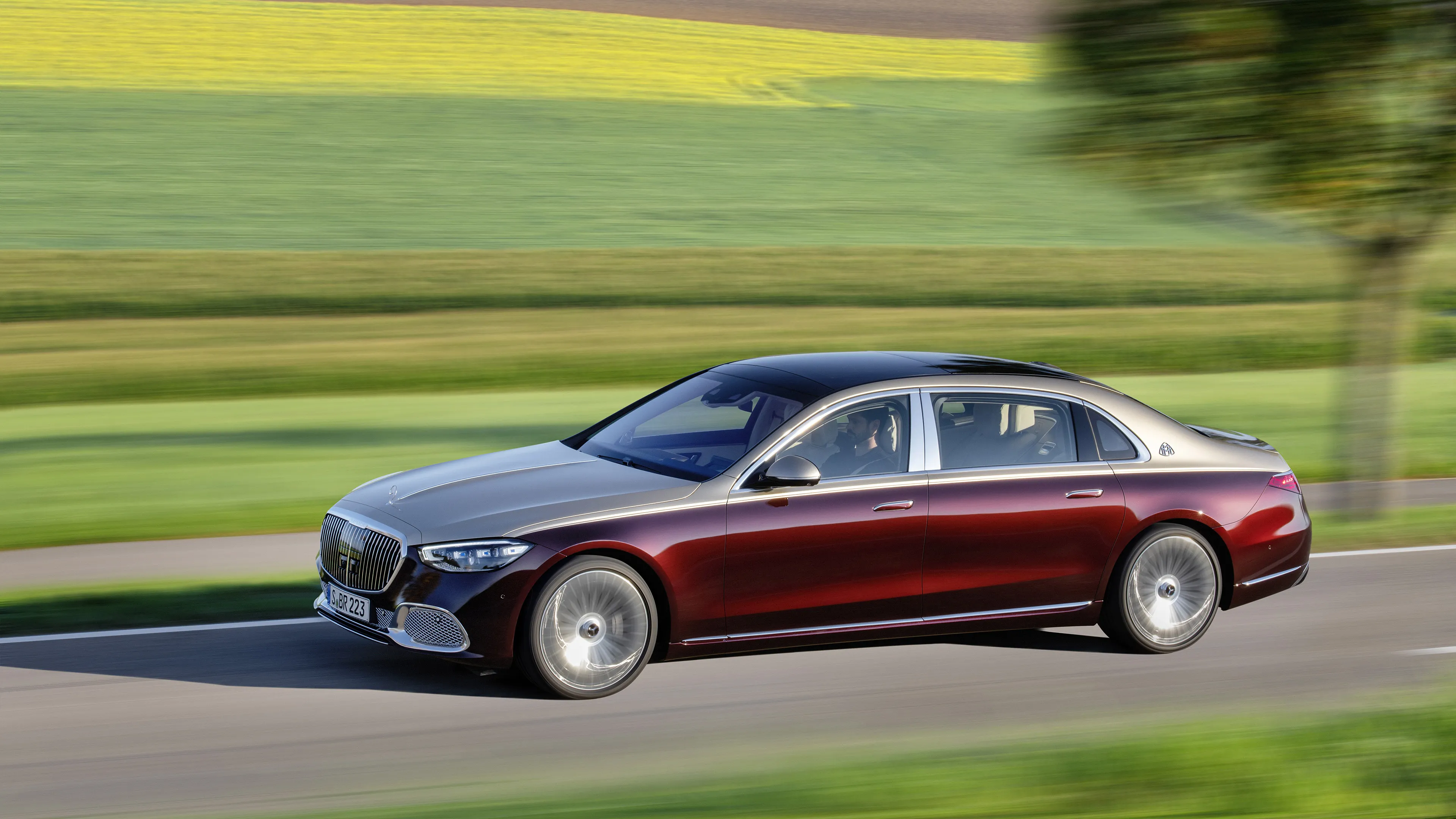 Red Mercedes Luxury Sedan Driving Through Green Fields
