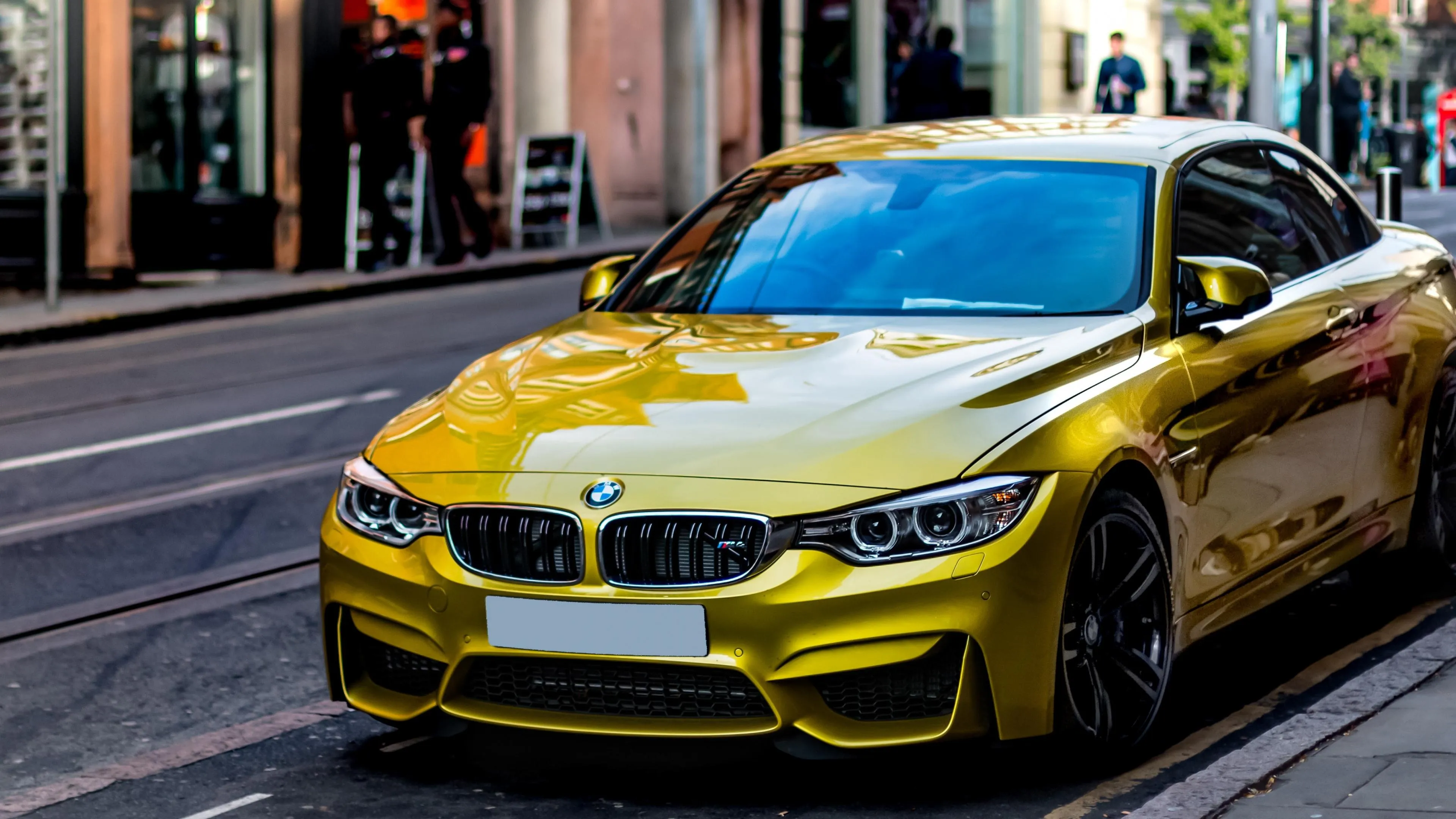Shiny Gold Bmw Driving Through City Street in Daylight