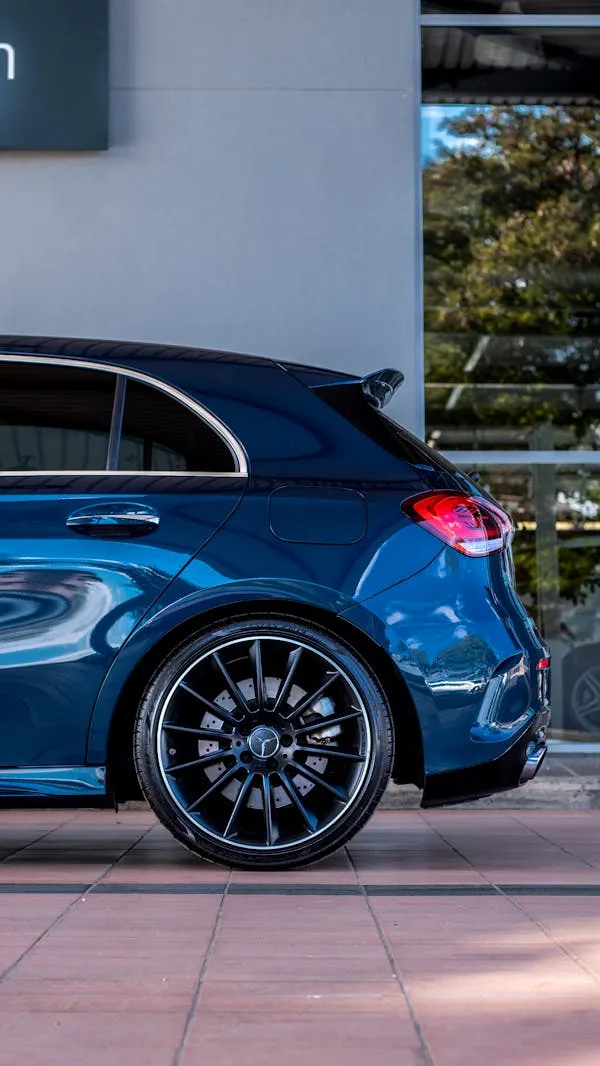Side view of blue Mercedes parked near glass building