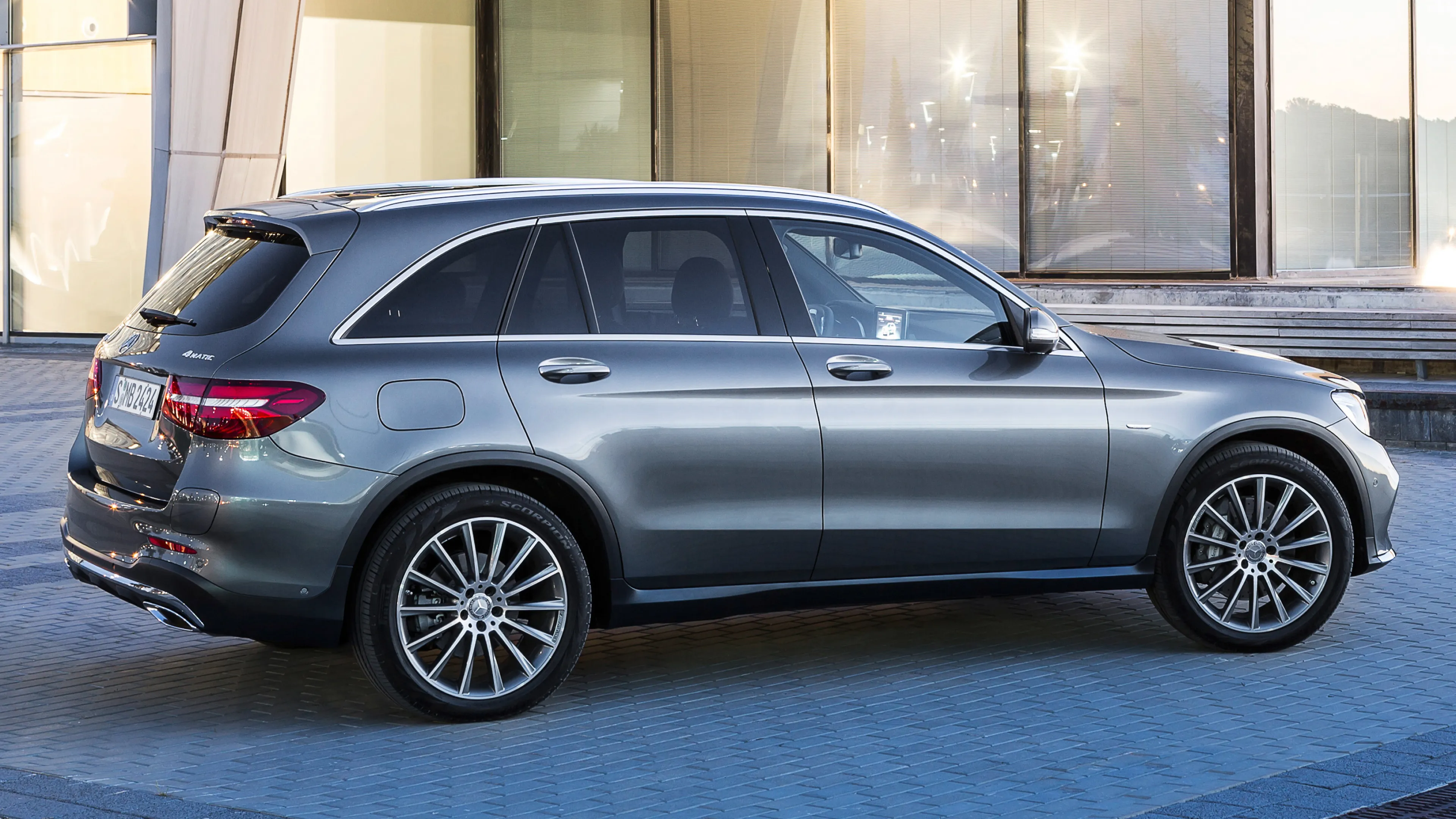 Side View of Grey Mercedes Benz SUV Against Glass Walls