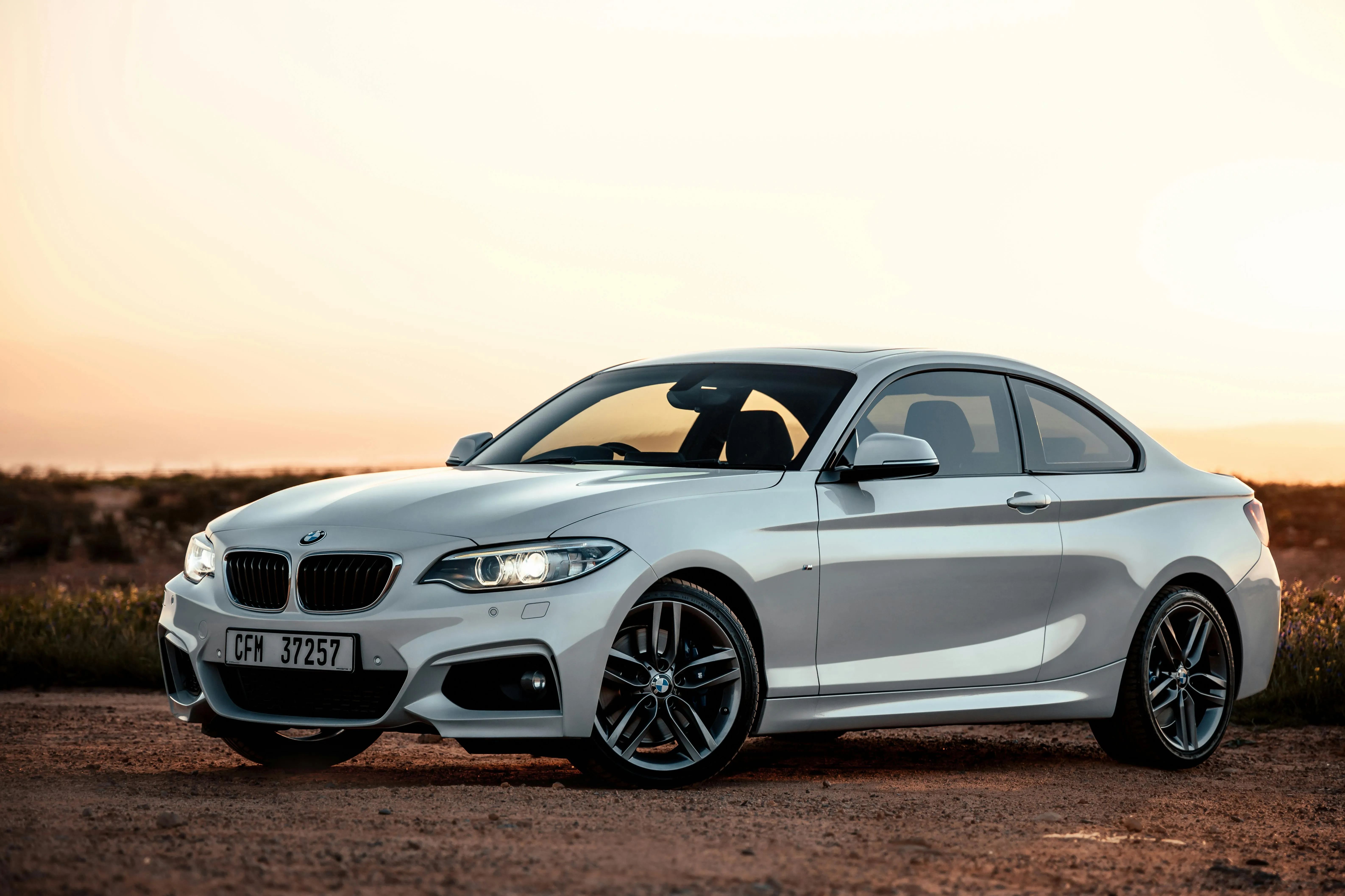 Silver Bmw Coupe Parked on Sand with Sunset in Background
