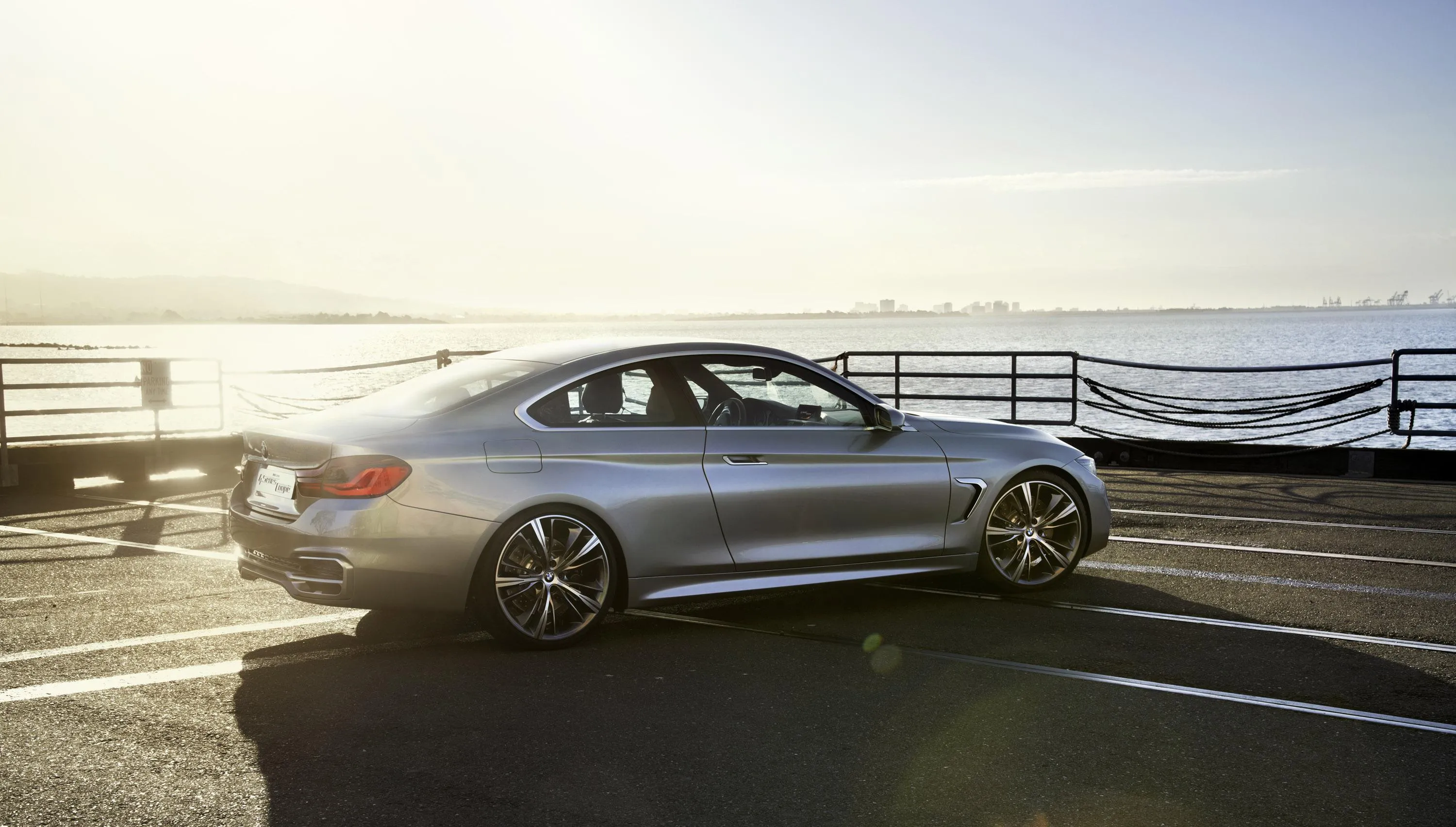 Silver Bmw Parked Near Ocean with Sun Low on the Horizon