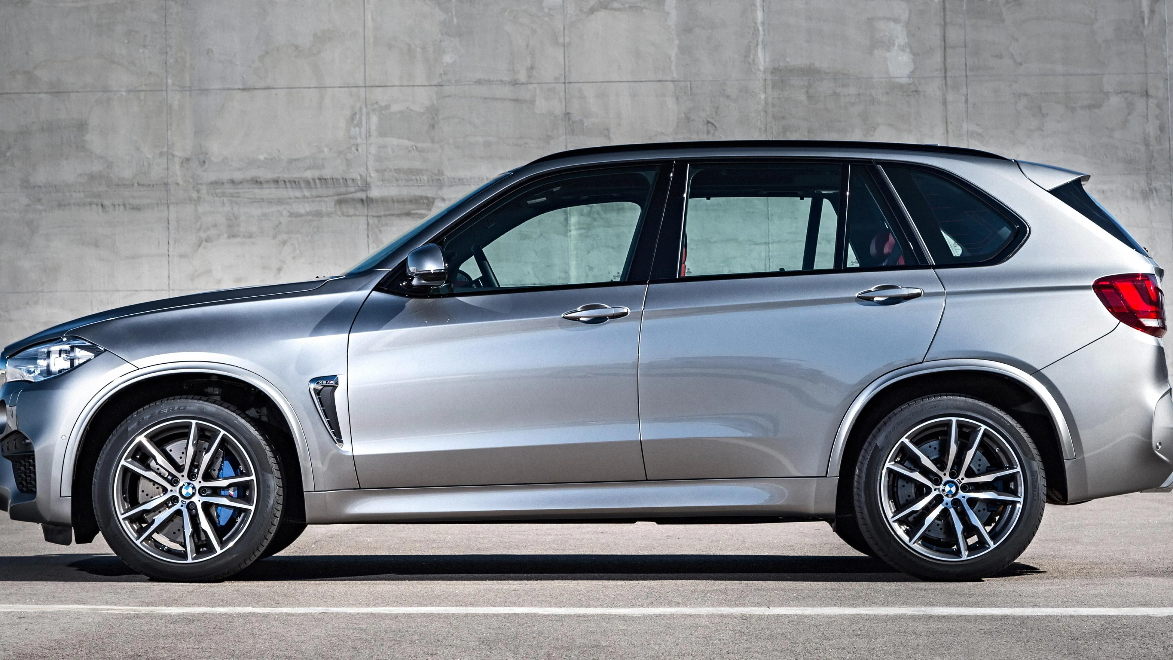 Silver Bmw Suv Parked Near Concrete Wall Under Natural Light