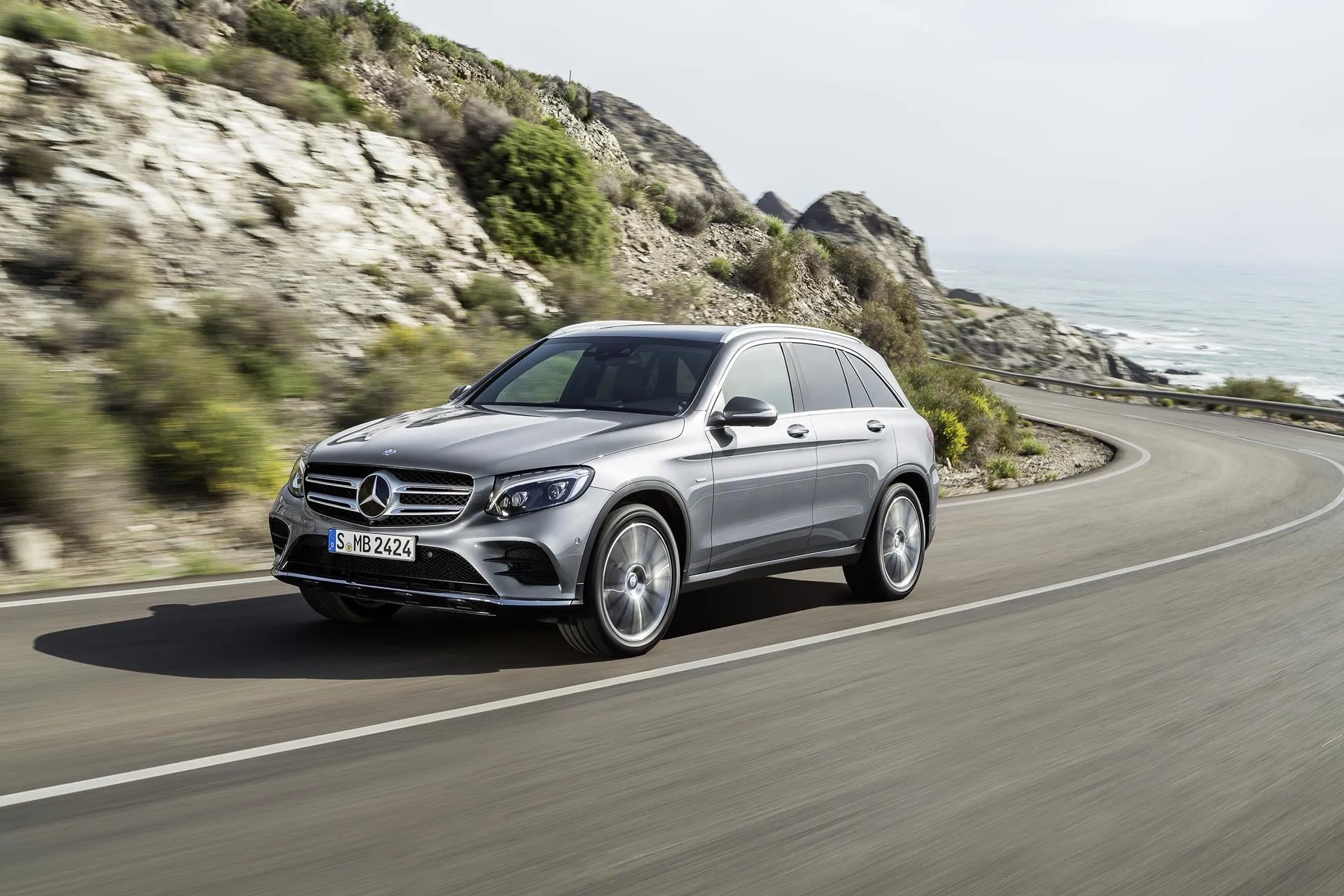 Silver Mercedes Benz SUV driving on a winding road Wallpaper
