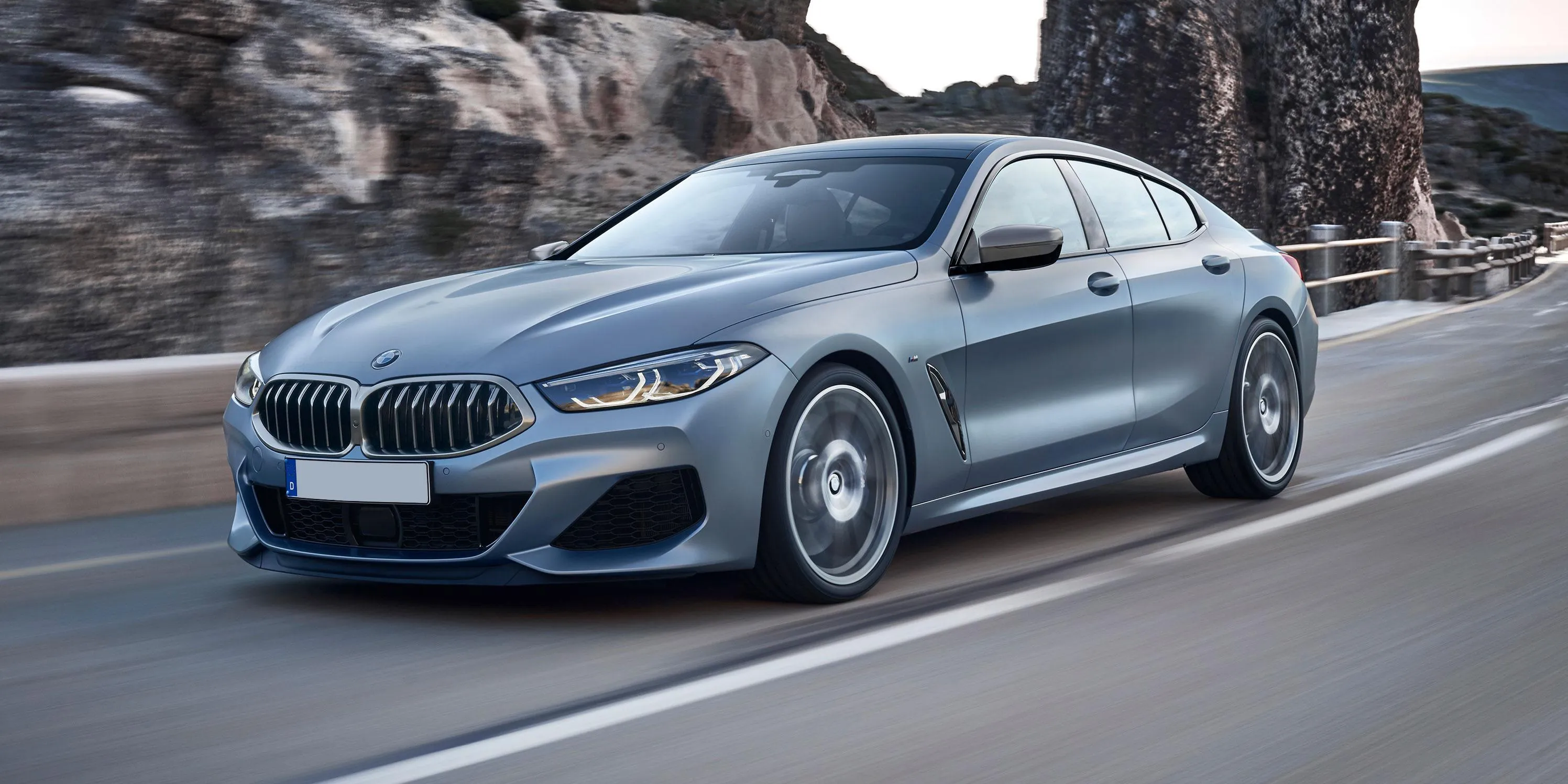 Sleek Gray Bmw Coupe Parked Near Rocky Landscape Image