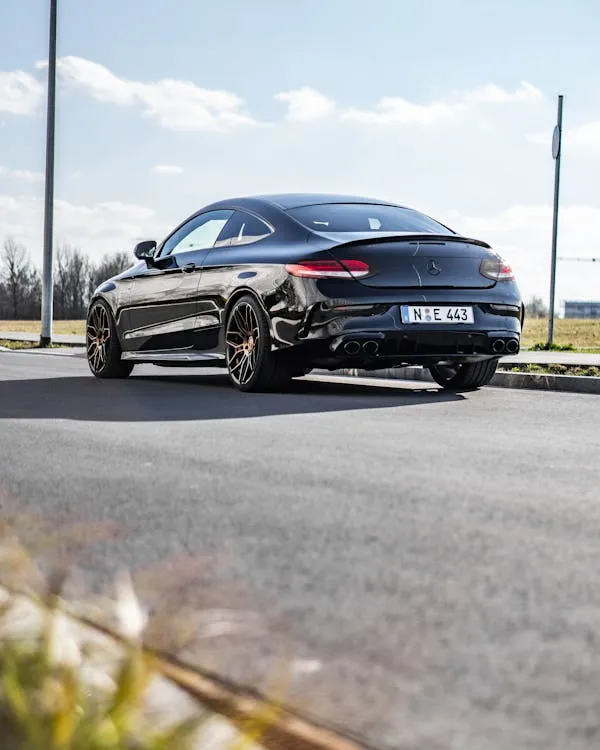 Sporty Black Mercedes Parked on Road with Blue Sky Wallpaper