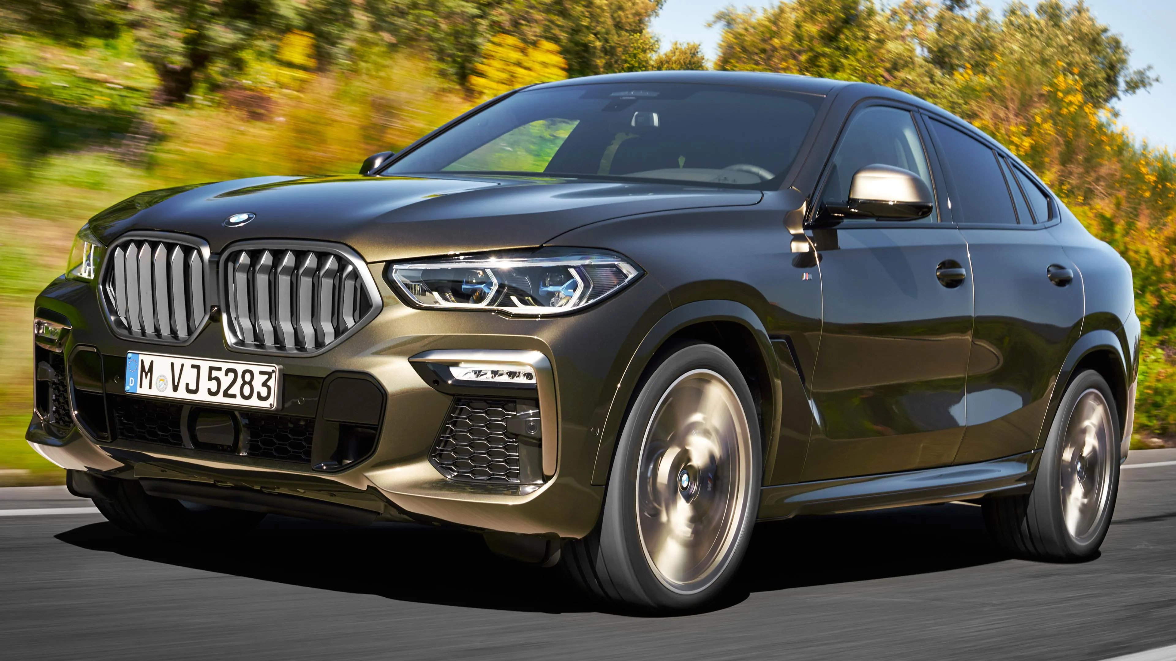 Sporty Bmw Suv Driving Through Autumn Scenery Wallpaper