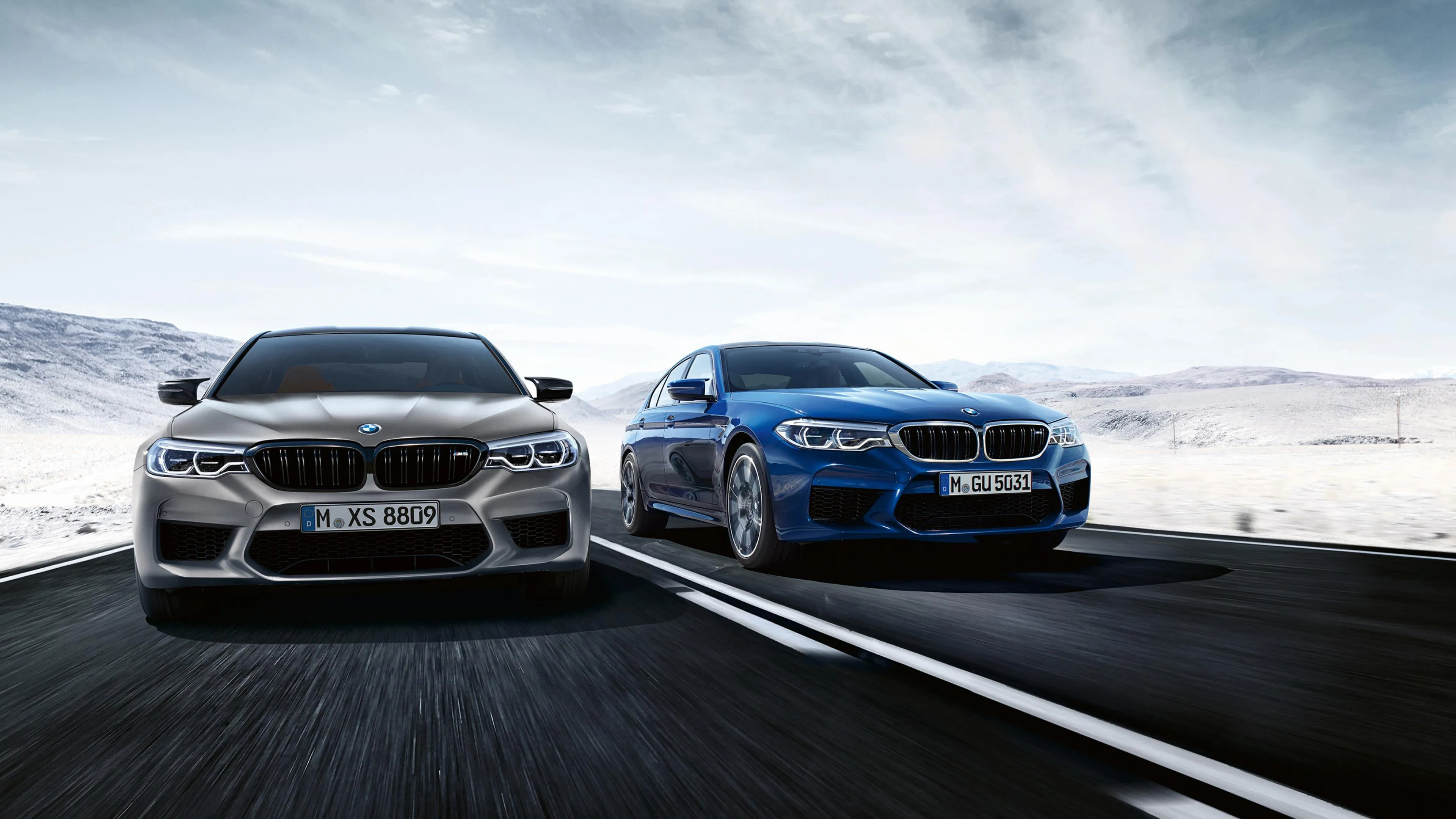 Two Bmw Cars Racing on Open Road Under Blue Sky Image