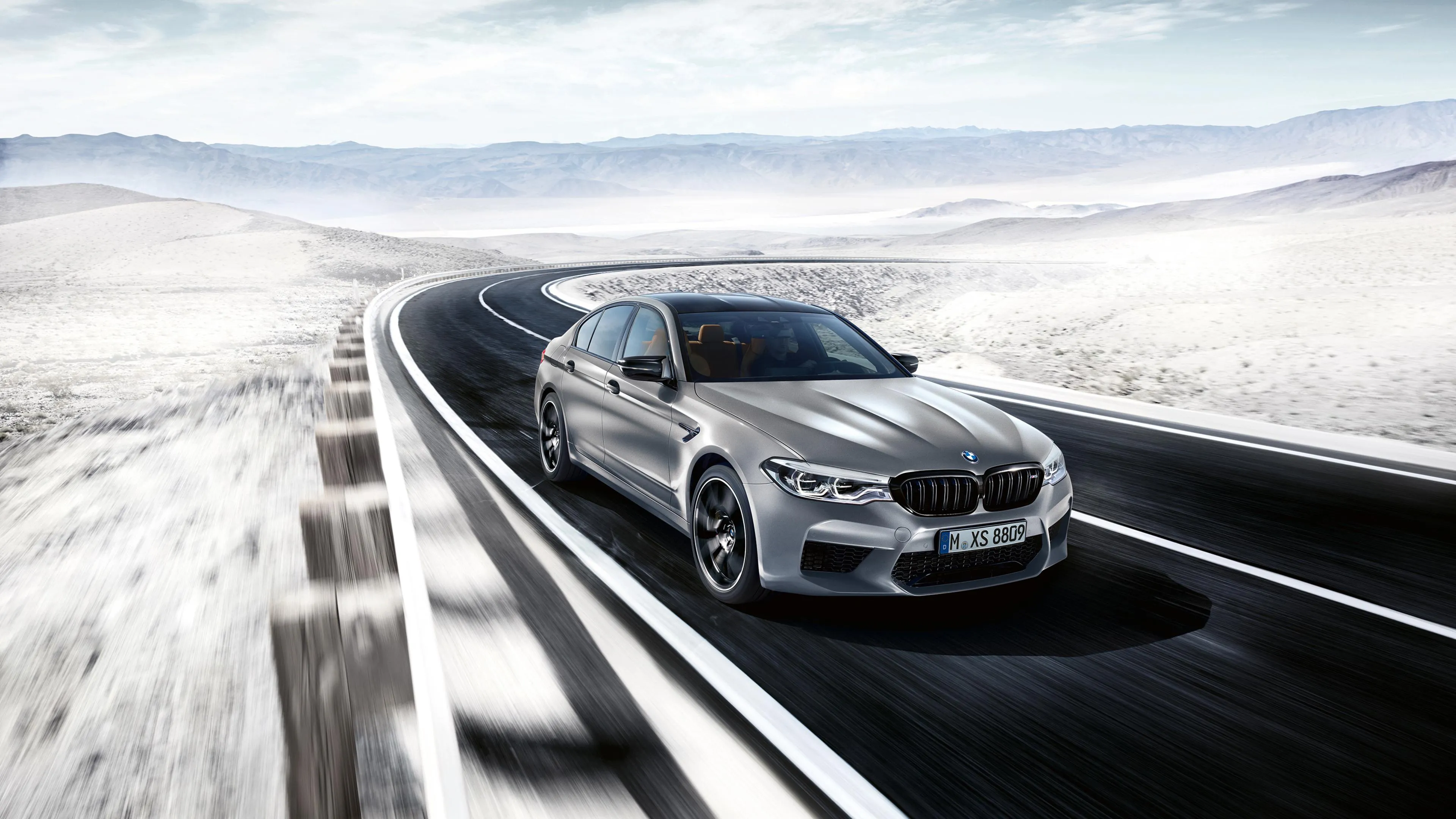 Two Bmws Driving Fast on a Snowy City Expressway Wallpaper