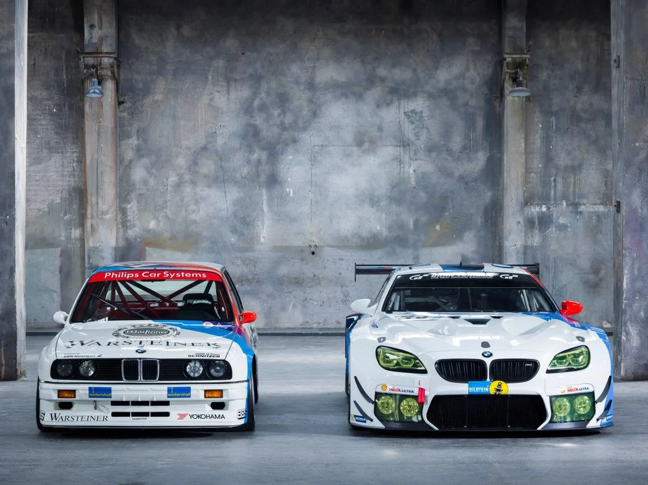 Two Classic Bmw Race Cars Parked Against Industrial Wall