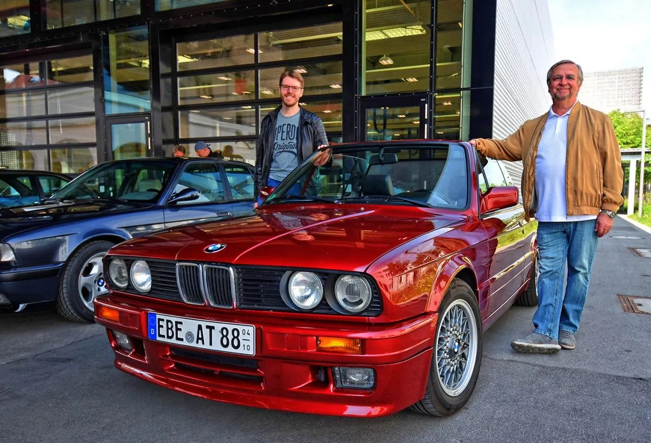 Two Men Standing Beside Bright Red Classic Bmw Car