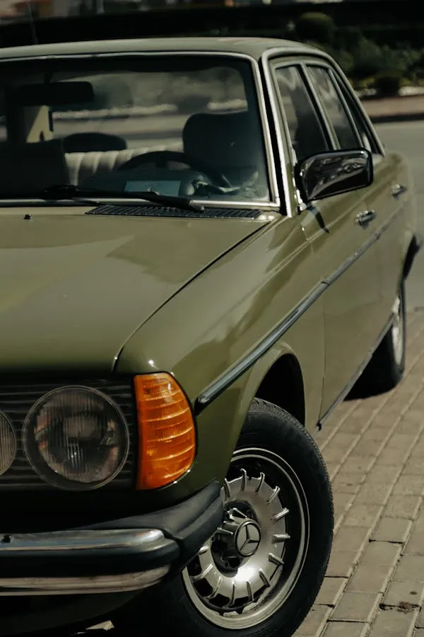Vintage olive Mercedes car parked on brick pavement