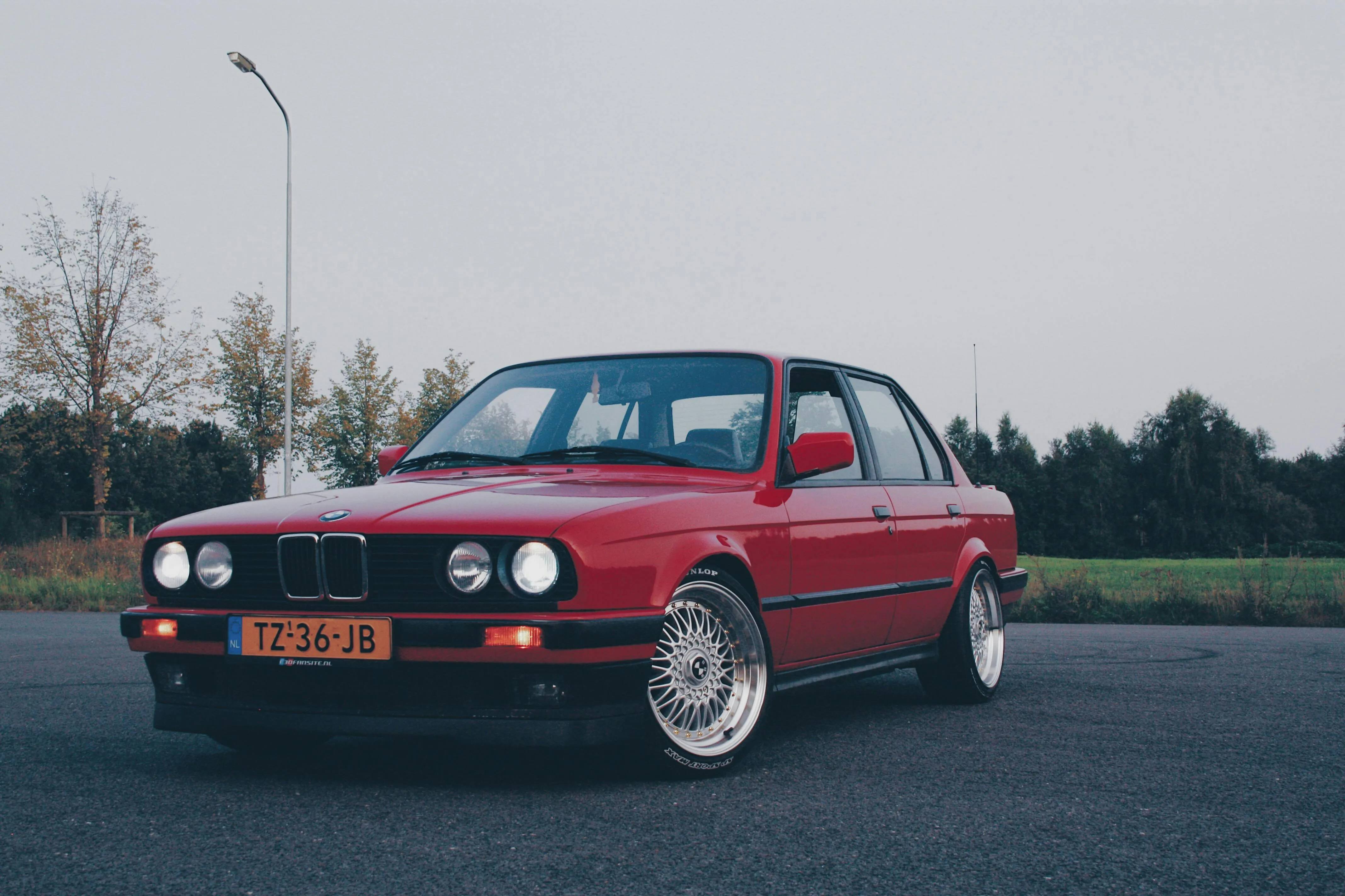 Vintage Red Bmw Parked on Road Under Cloudy Sky Wallpaper