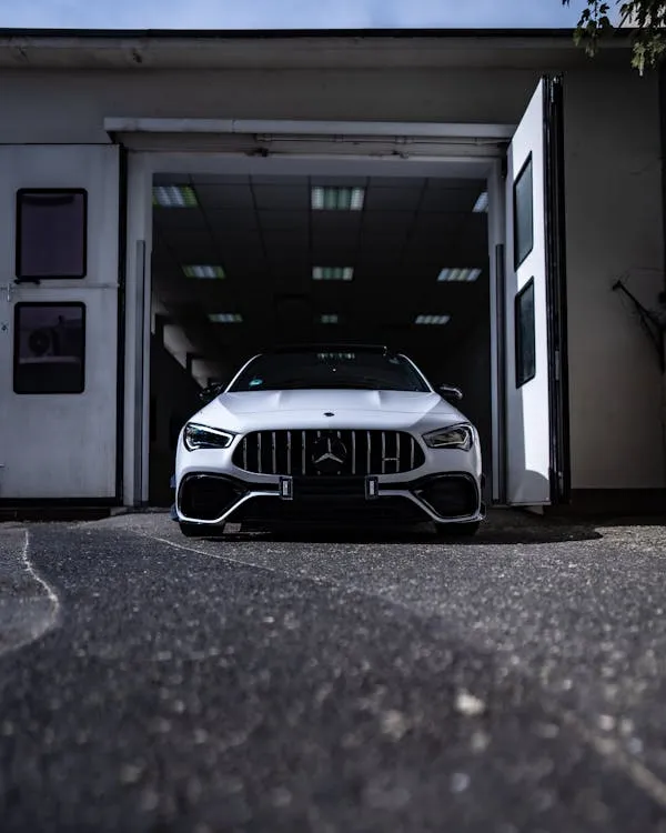 White AMG Parked Inside Garage with Open Doors View image