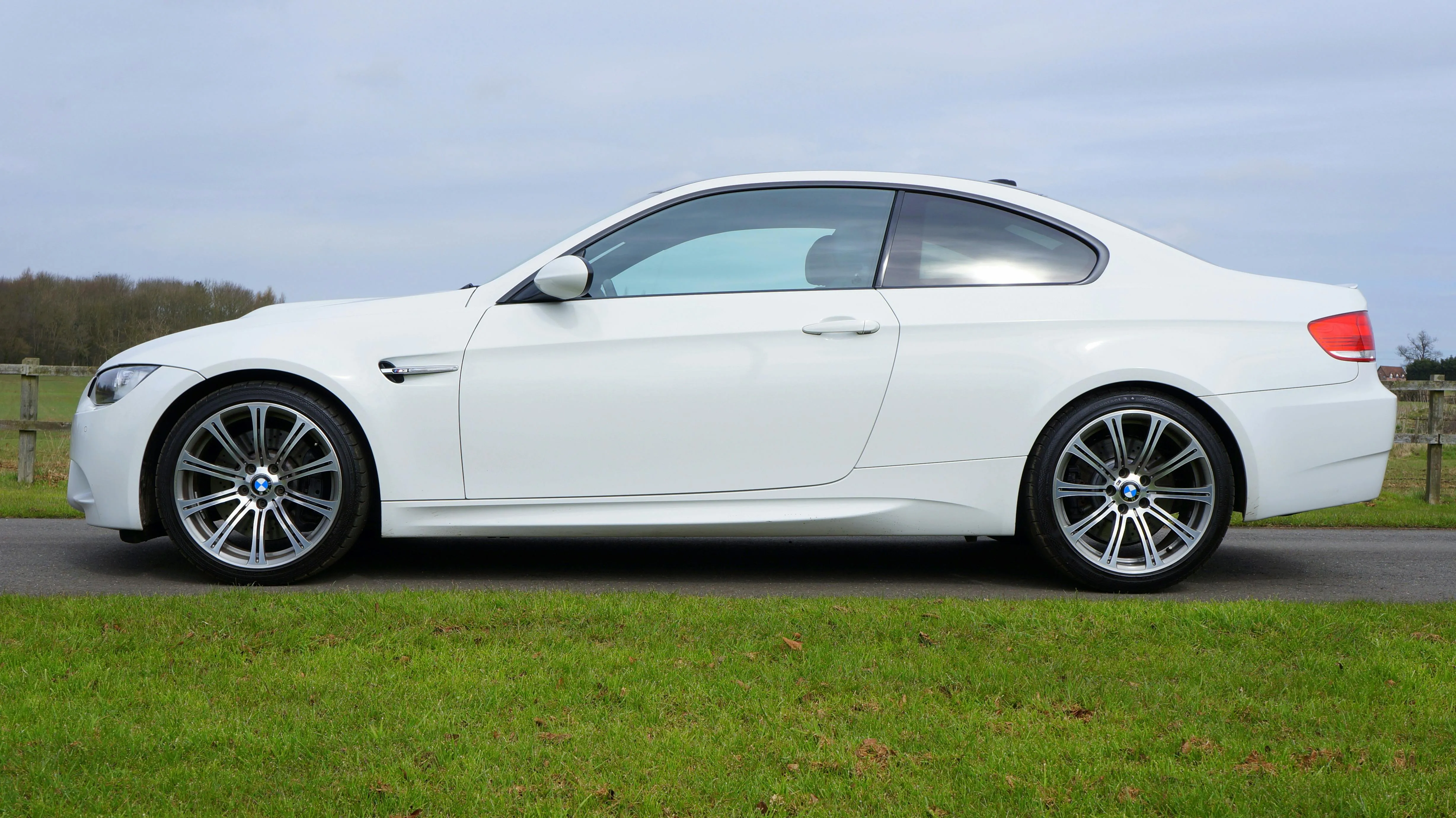 White Bmw Coupe Parked on Grassy Field Near Trees and Sky