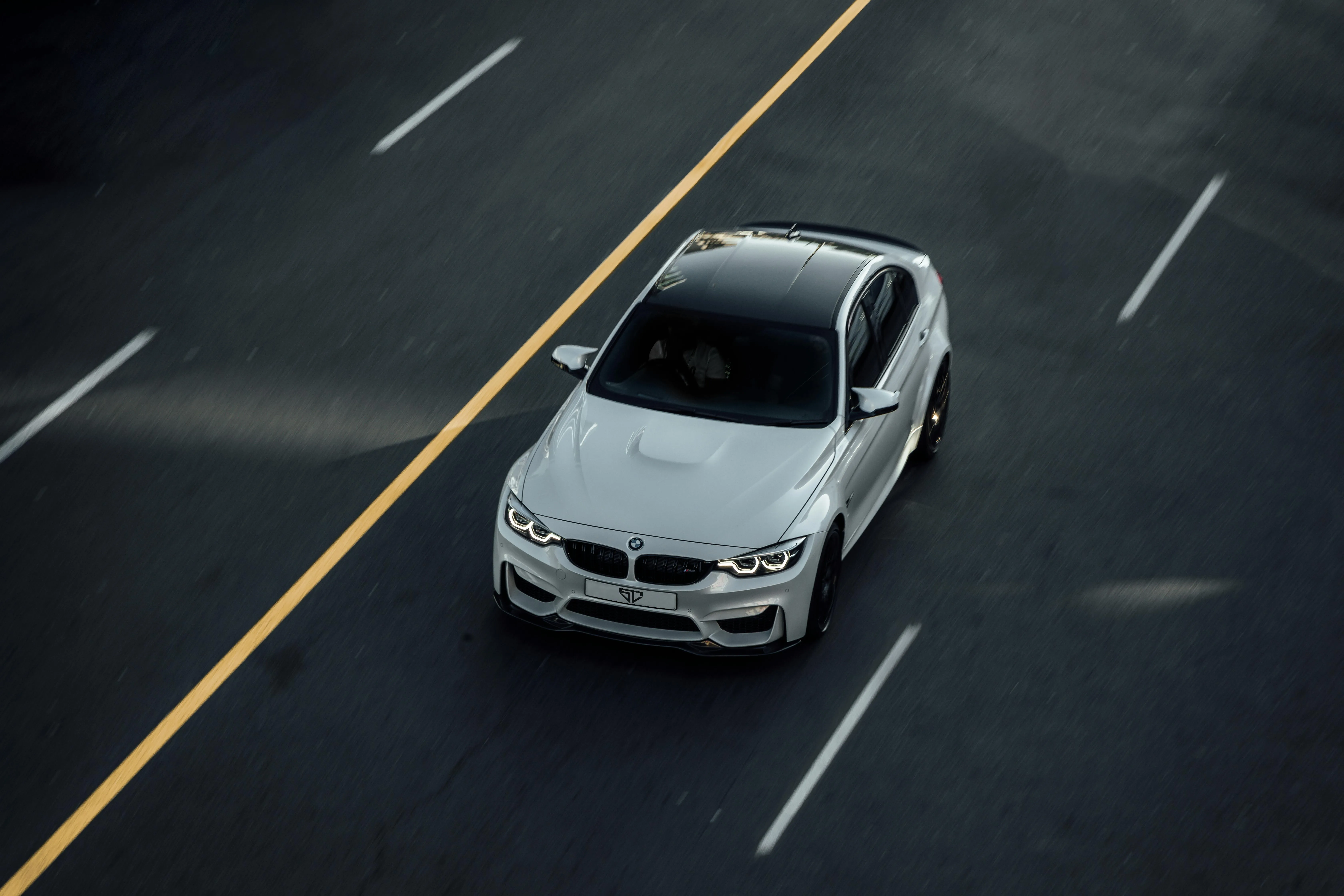 White Bmw Driving on Empty Multi Lane Road Overhead