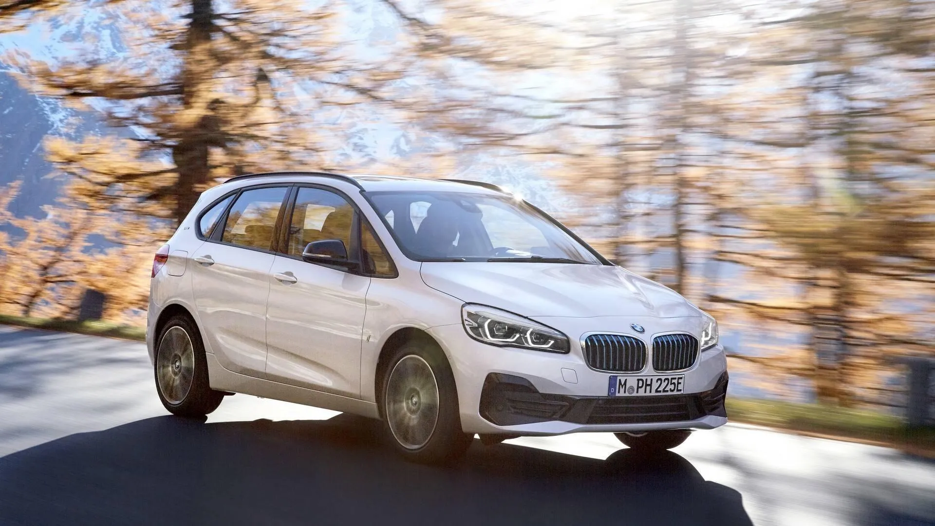 White Bmw Driving Through Autumn Forest Mountain Road