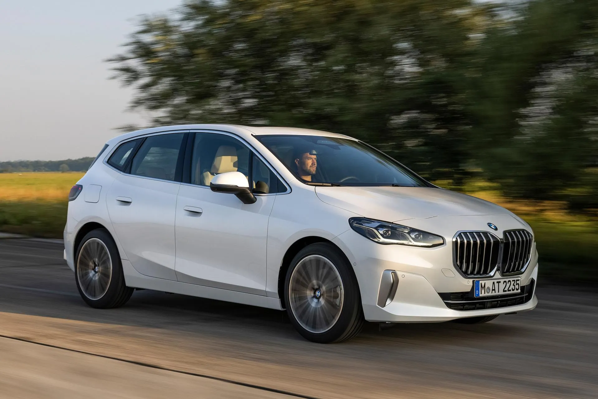 White Bmw Hatchback Driving on a Tree Lined Road Wallpaper