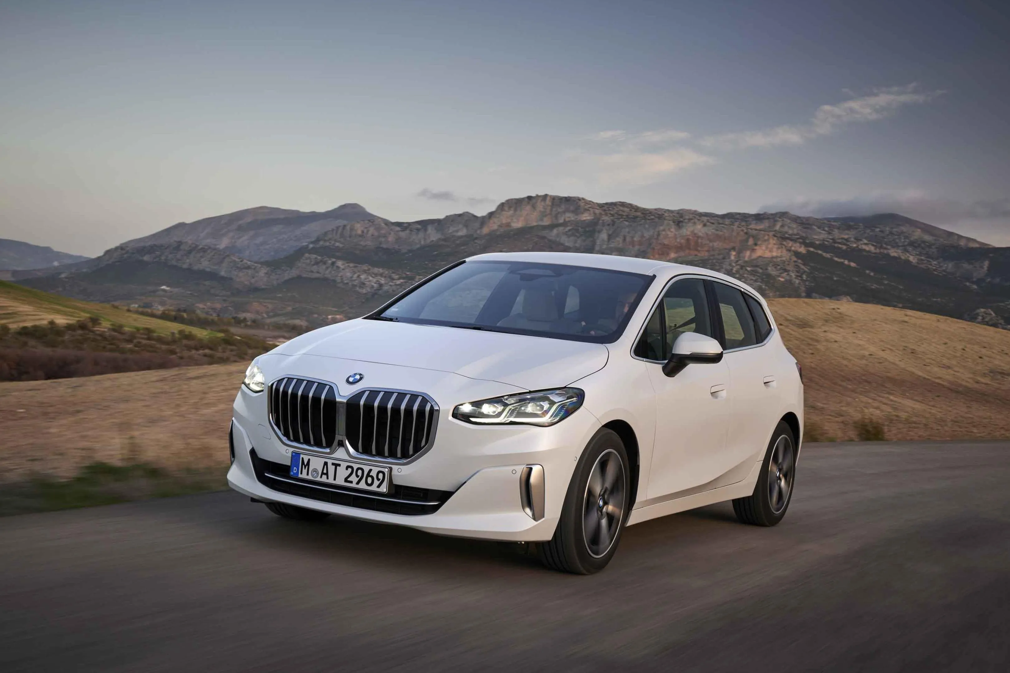 White Bmw on Road with Dry Hills and Mountains in Back