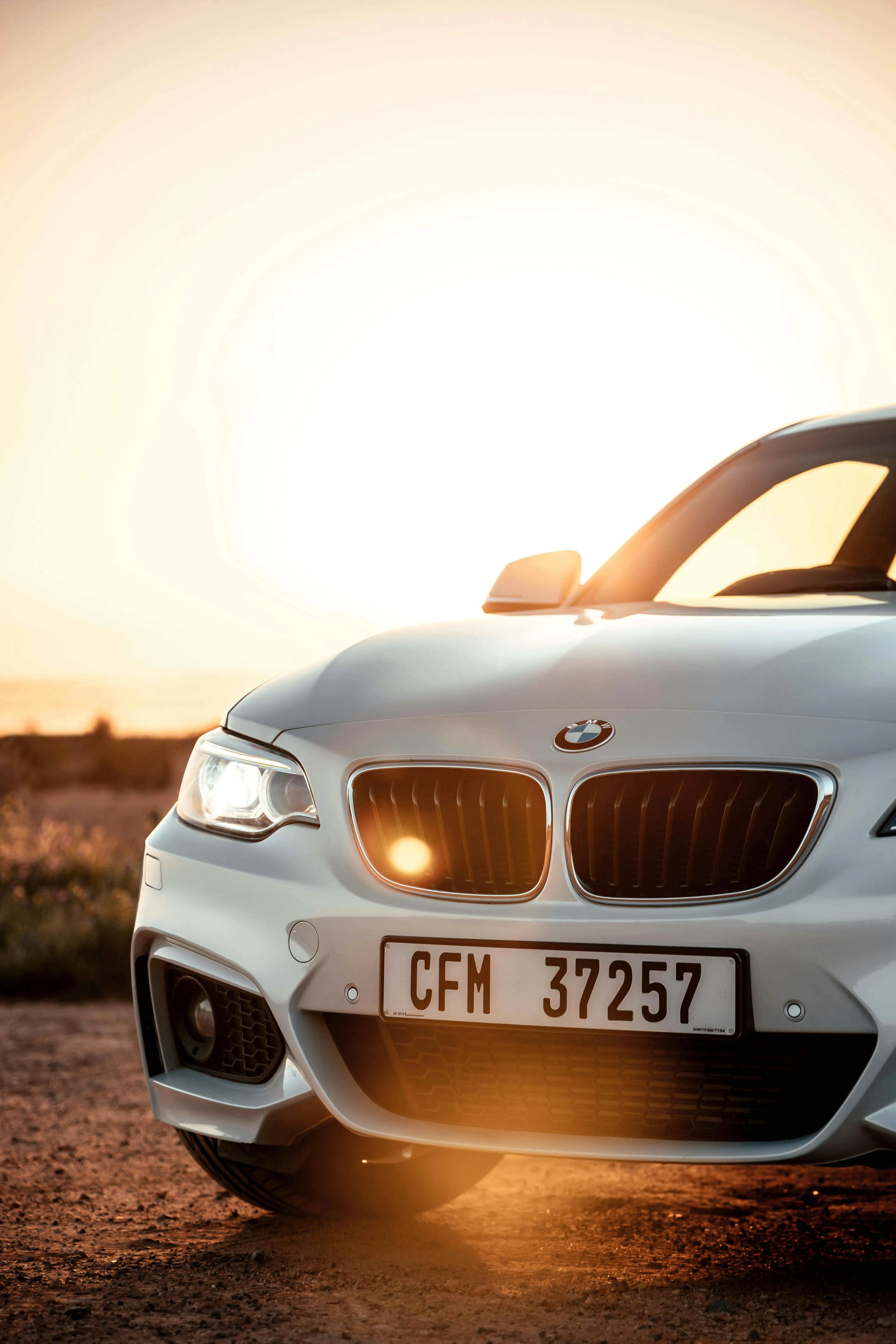 White Bmw Parked Under Sunlight with Front Lights On