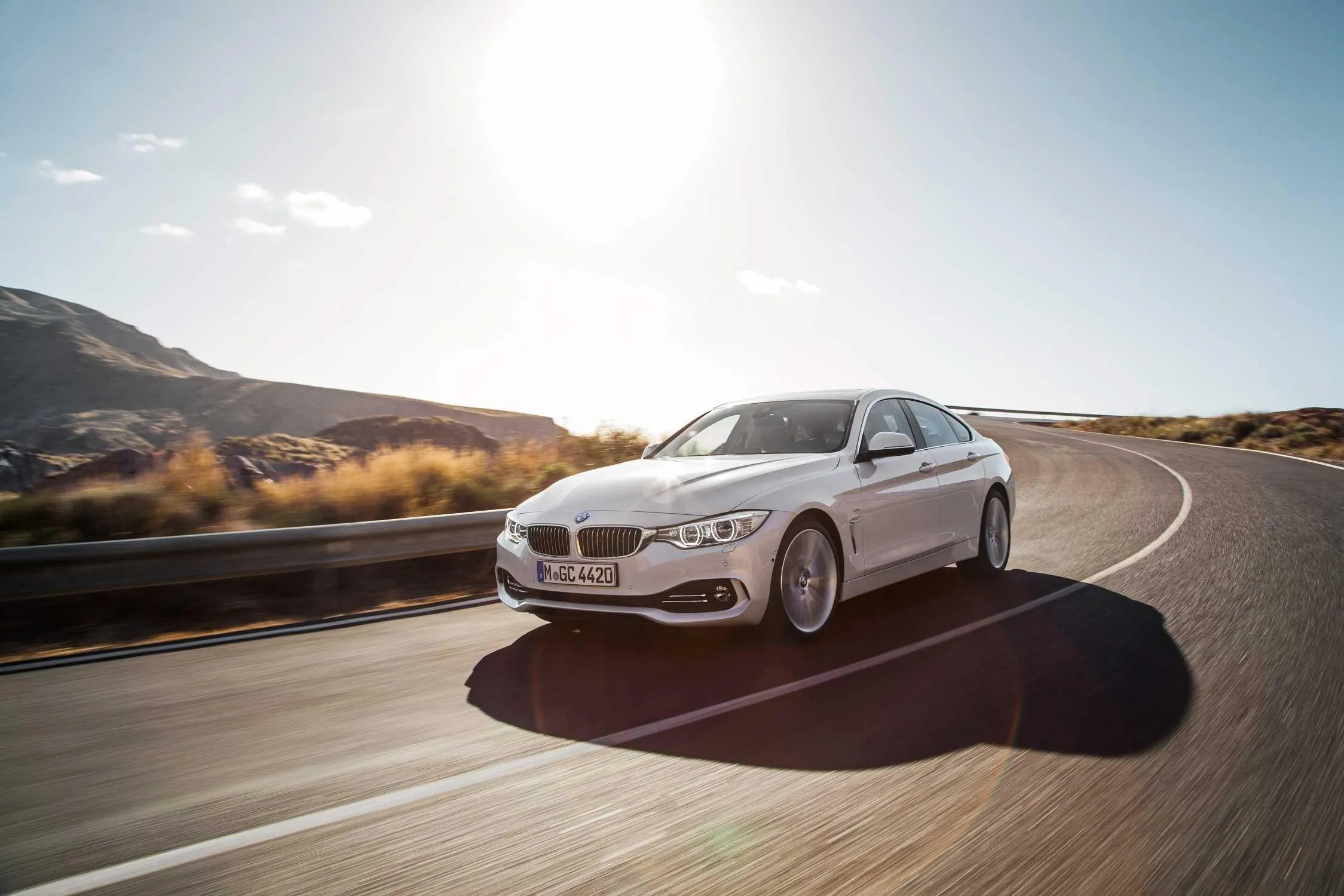White Bmw Sedan Cruising Down a Desert Highway Image
