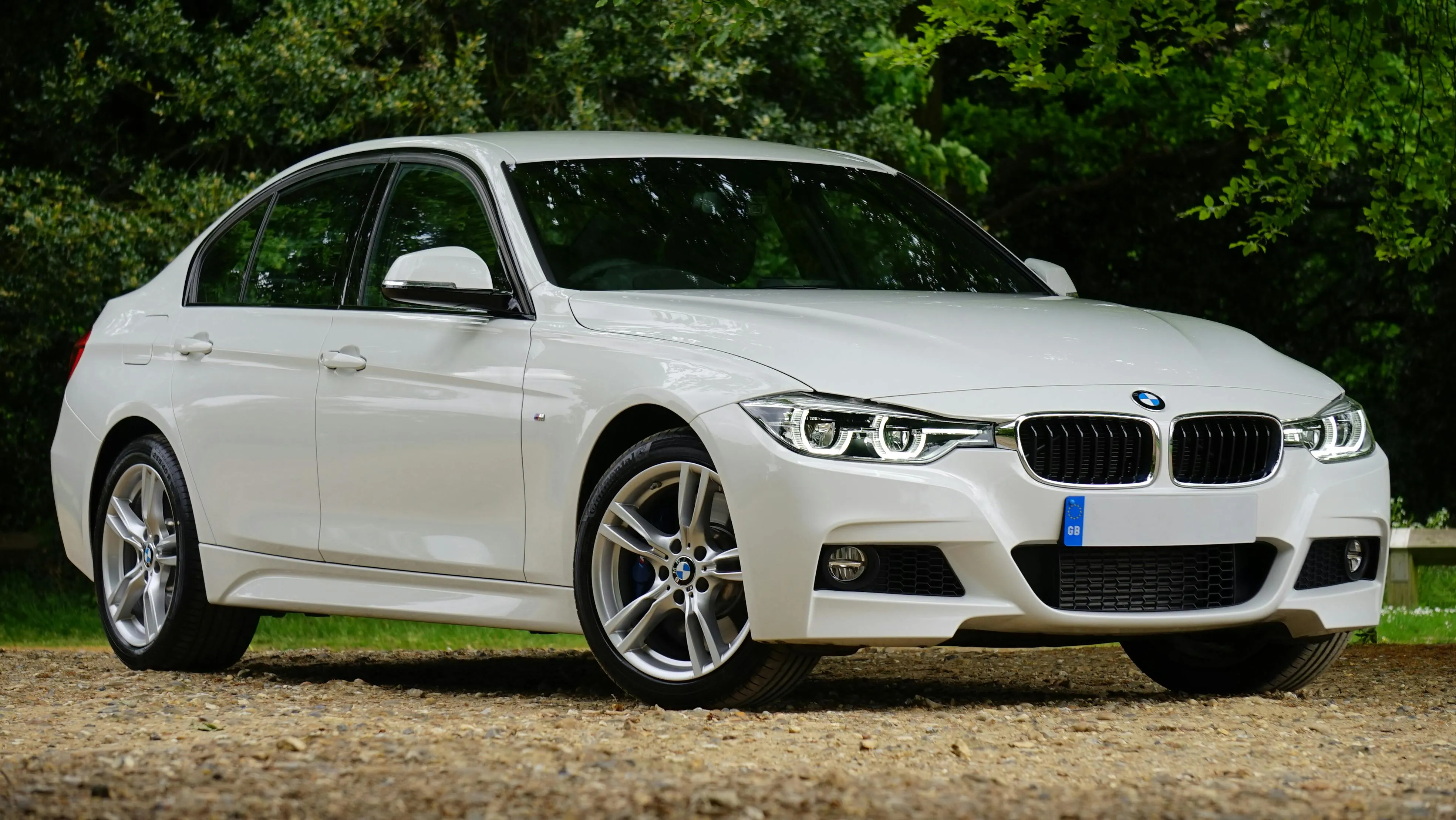 White Bmw Sedan Parked By Lush Green Landscape Wallpaper