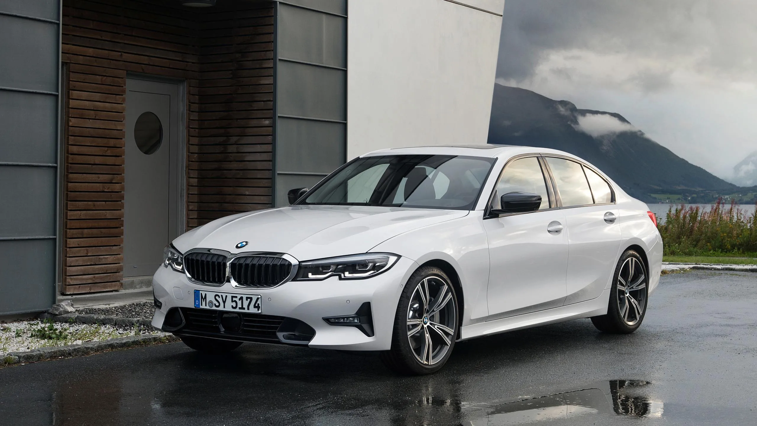White Bmw Sedan Parked in Front of Building on Wet Ground