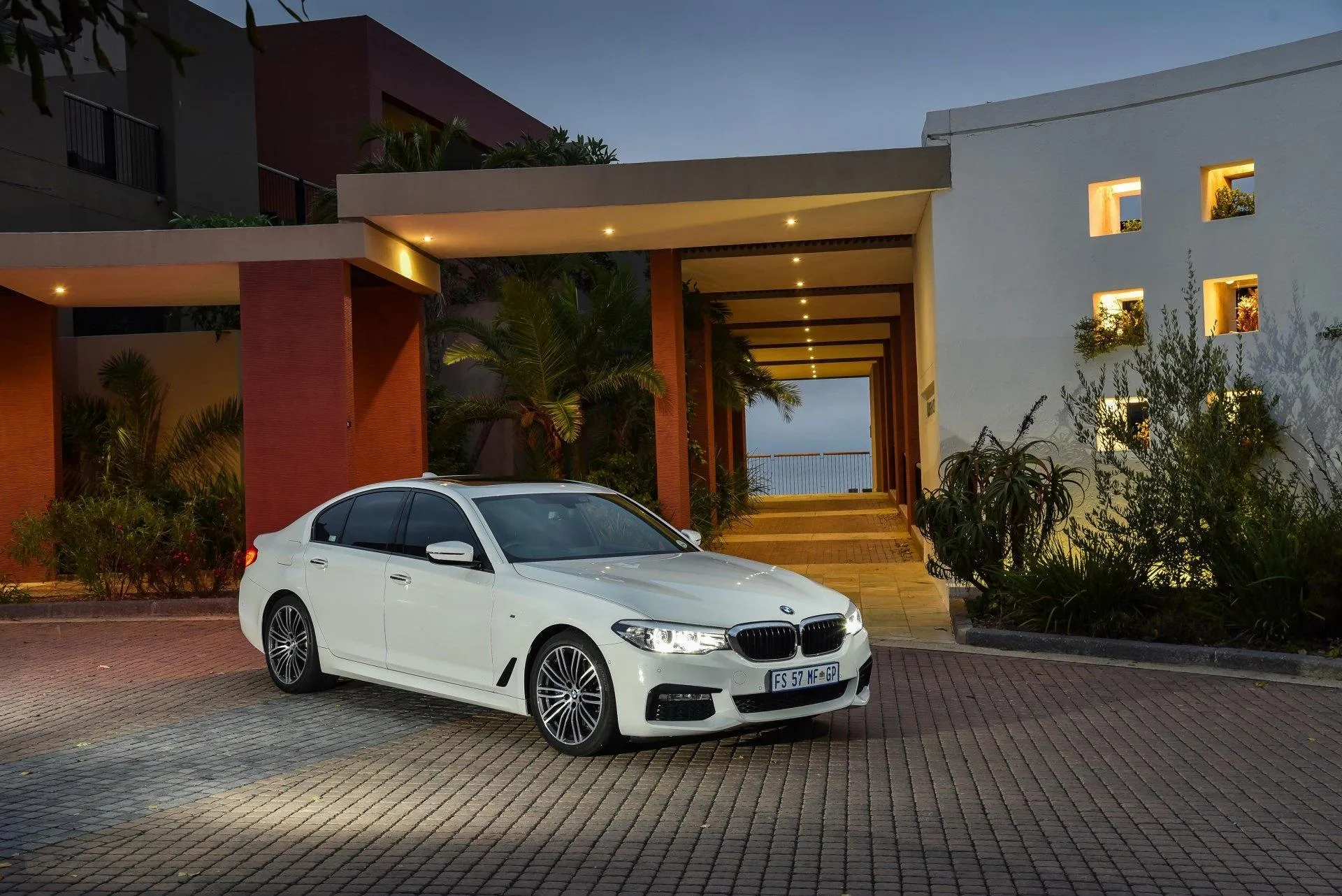 White Bmw Sedan Parked Outside Modern Home at Night