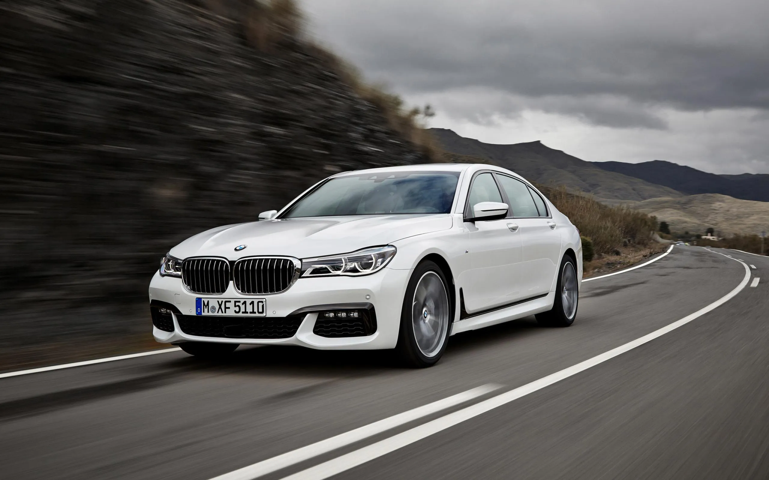 White Bmw Sedan Speeding Along Mountain Road Wallpaper