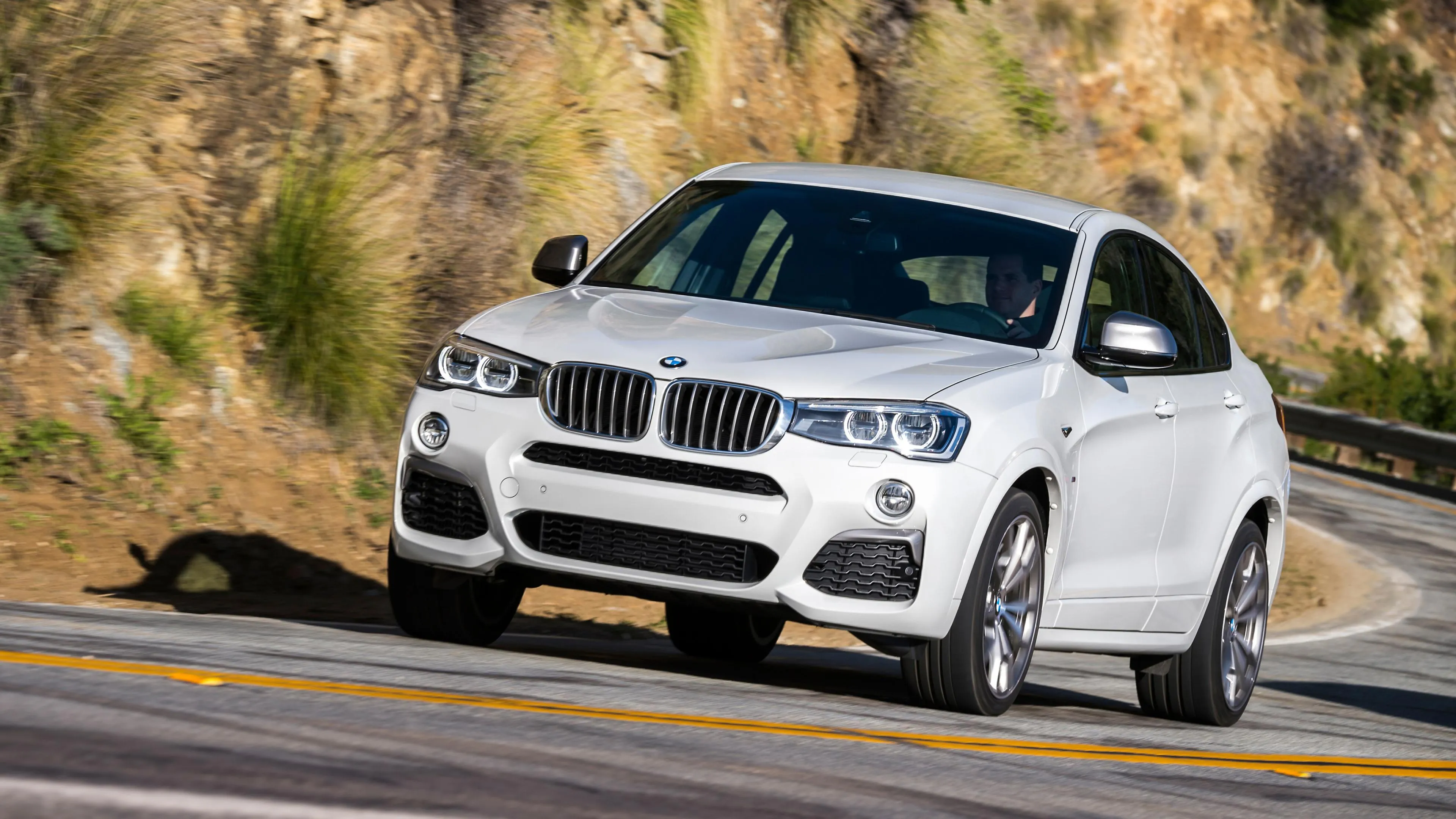 White Bmw Suv Driving Fast Along a Winding Road Image